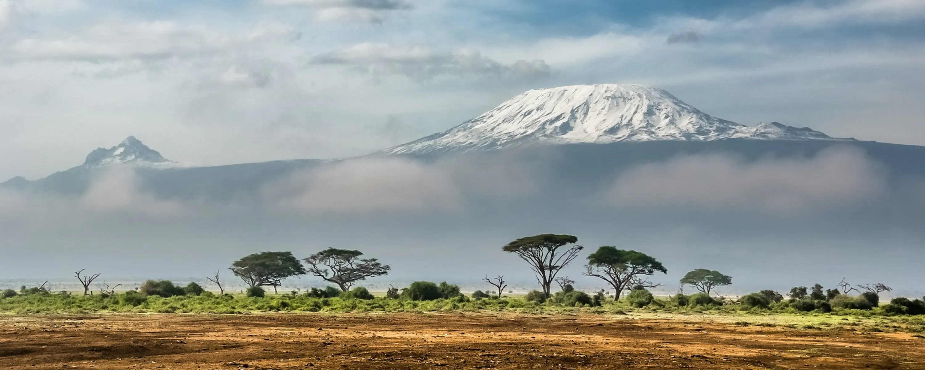 Mount Kenya rising above golden plains in Kenya's Laikipia, under expansive skies beneath dramatic skies.
