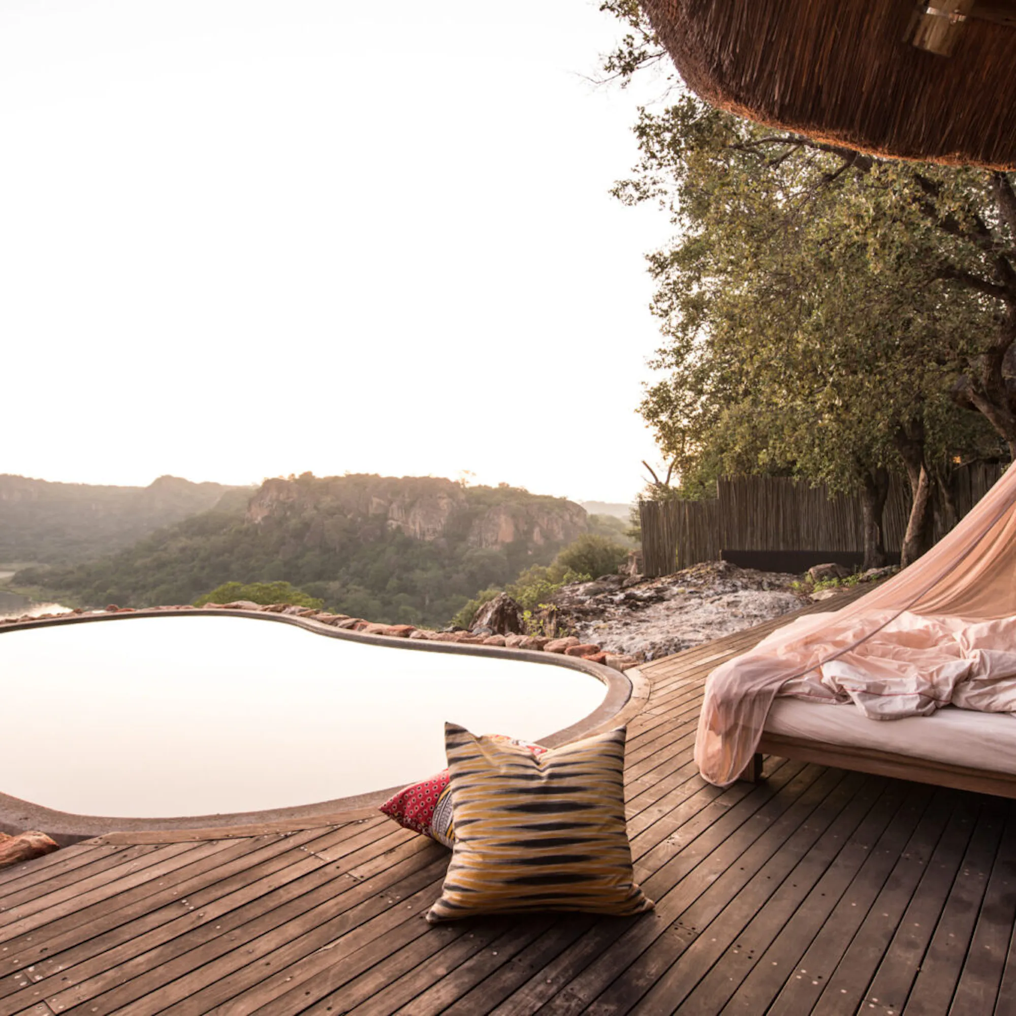 A star bed overlooking still water and distant hills at dusk at Singita Pamushana in Zimbabwe's Malilangwe Reserve.