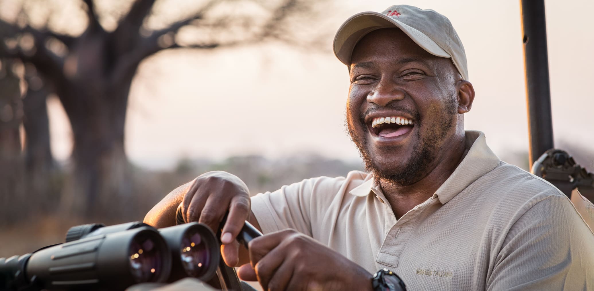 A guide laughs, as he poses for a portrait as warm sunrise light fills the scene