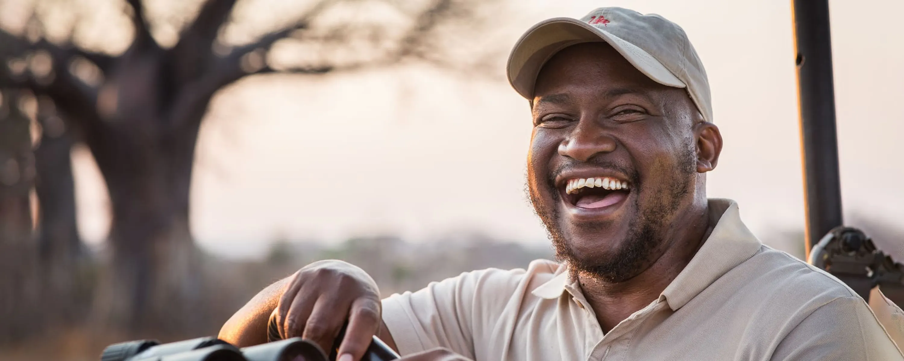 A guide laughs, as he poses for a portrait as warm sunrise light fills the scene