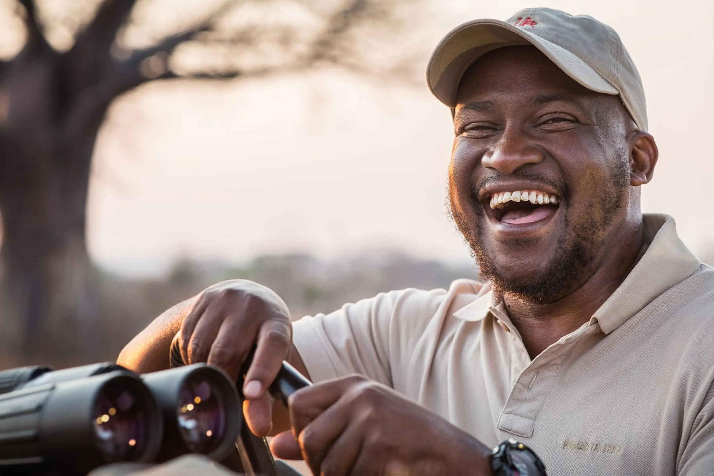 A guide laughs, as he poses for a portrait as warm sunrise light fills the scene