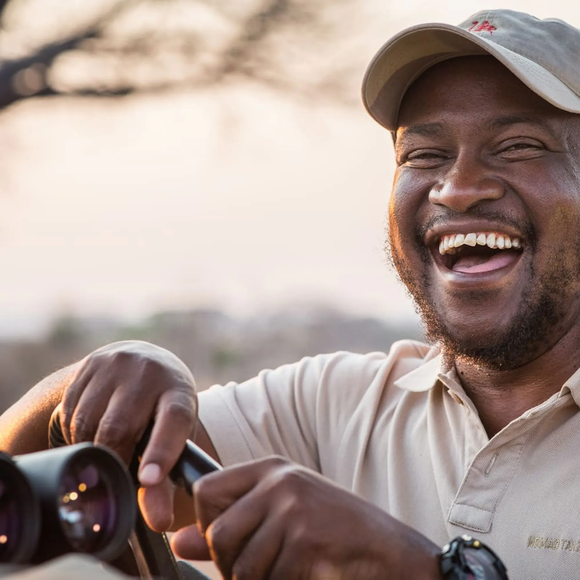 A guide laughs, as he poses for a portrait as warm sunrise light fills the scene