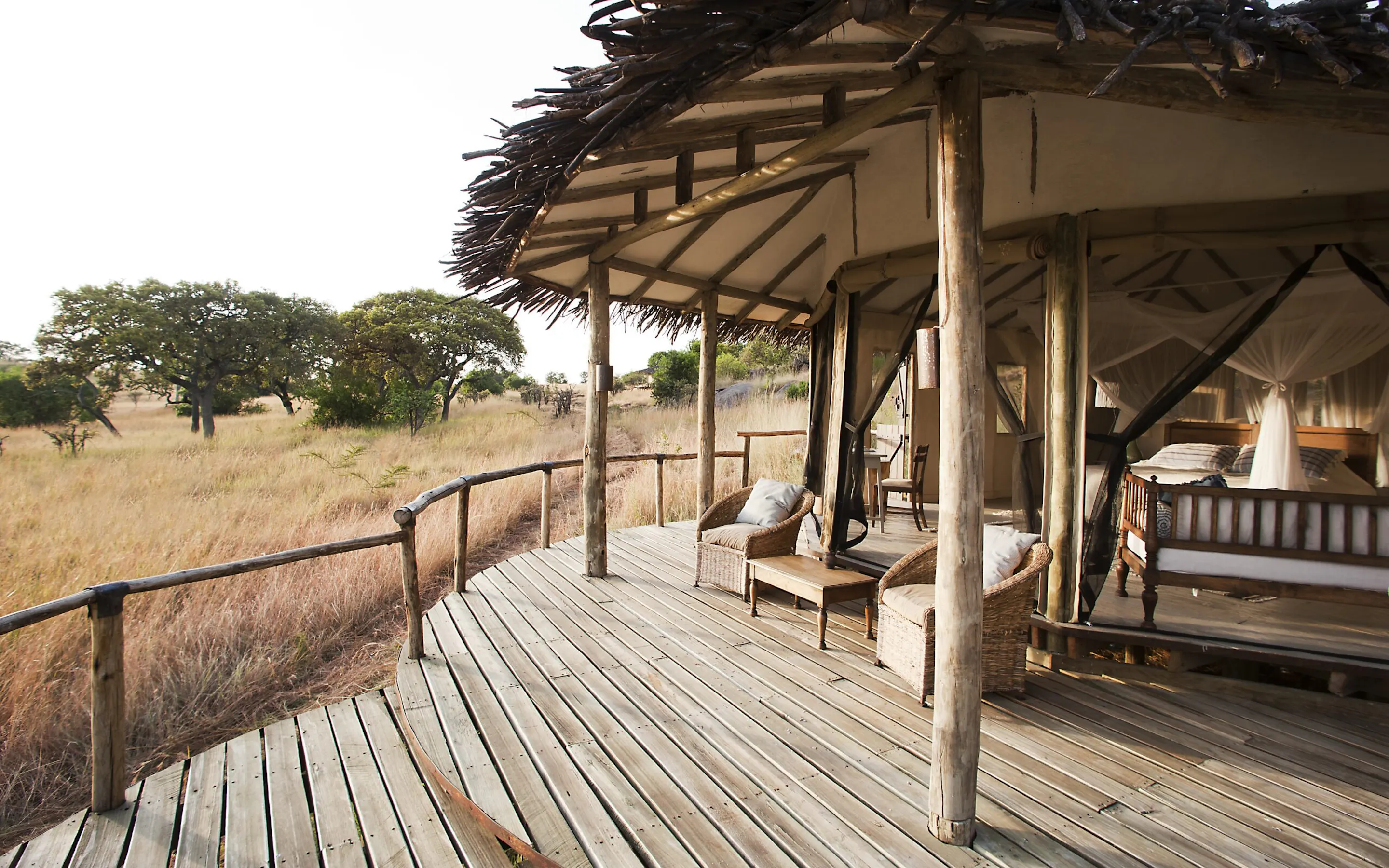 An open safari deck overlooking grassland and water at dusk against the backdrop of Tanzania's Serengeti.