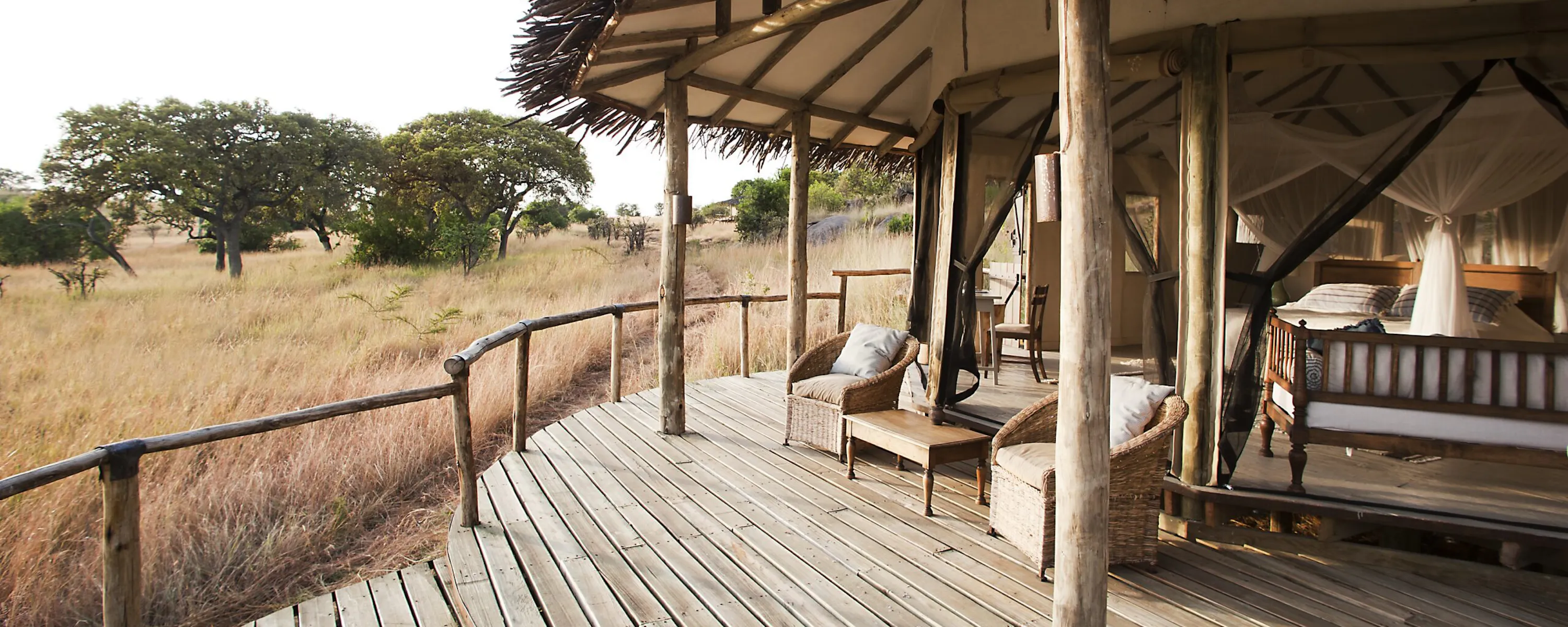 An open safari deck overlooking grassland and water at dusk against the backdrop of Tanzania's Serengeti.