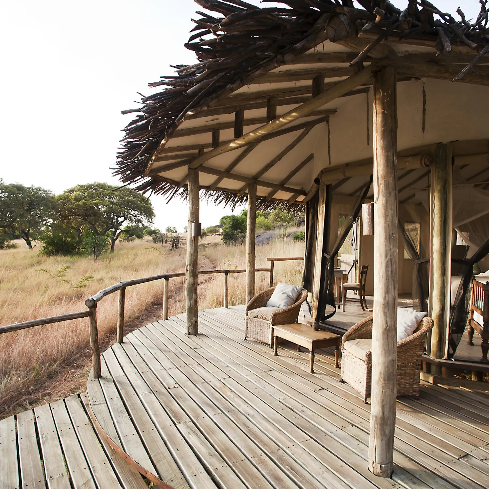 An open safari deck overlooking grassland and water at dusk against the backdrop of Tanzania's Serengeti.