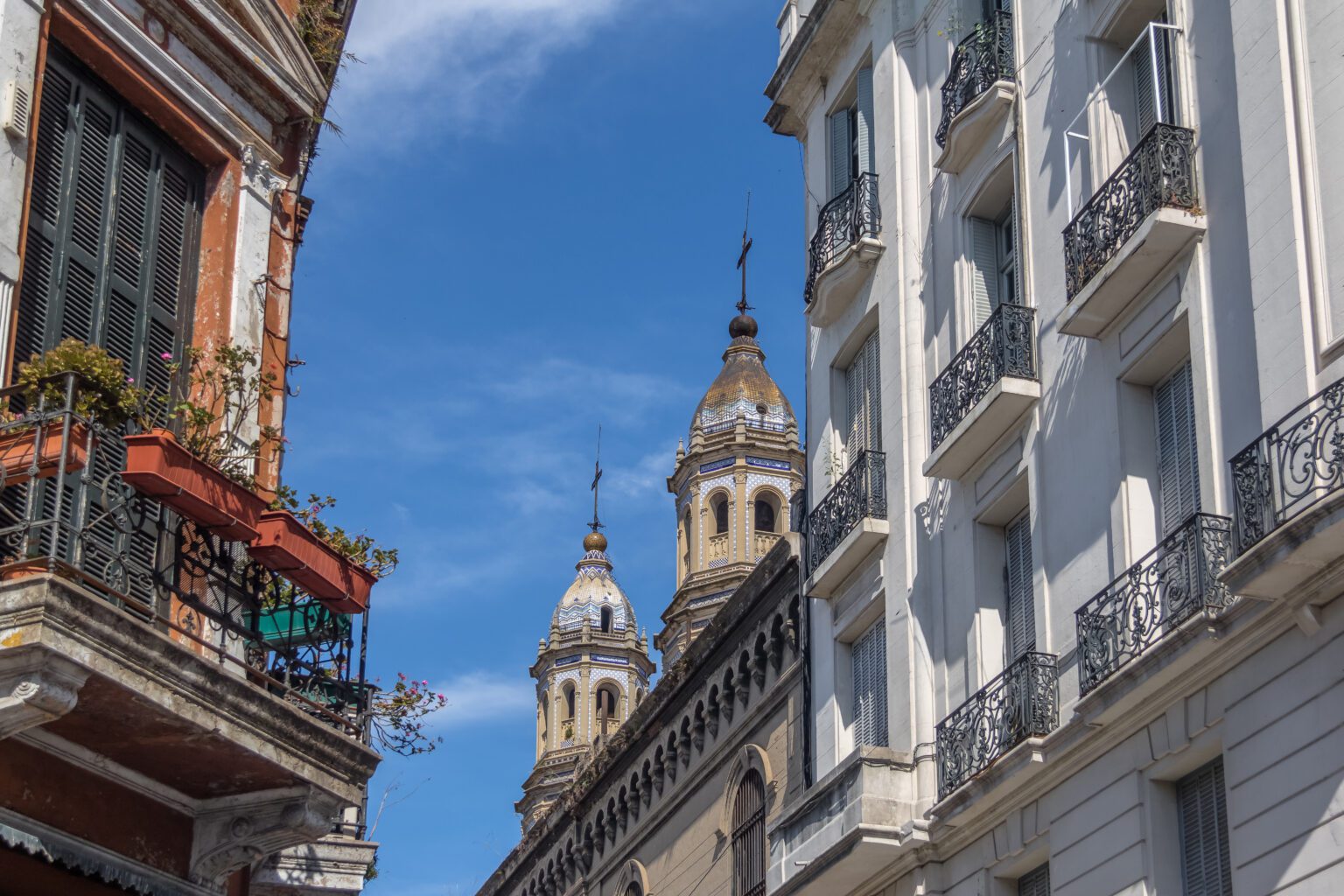 San Pedro Telmo Church rises between pastel buildings in Buenos Aires, seen from a narrow cobbled street below.