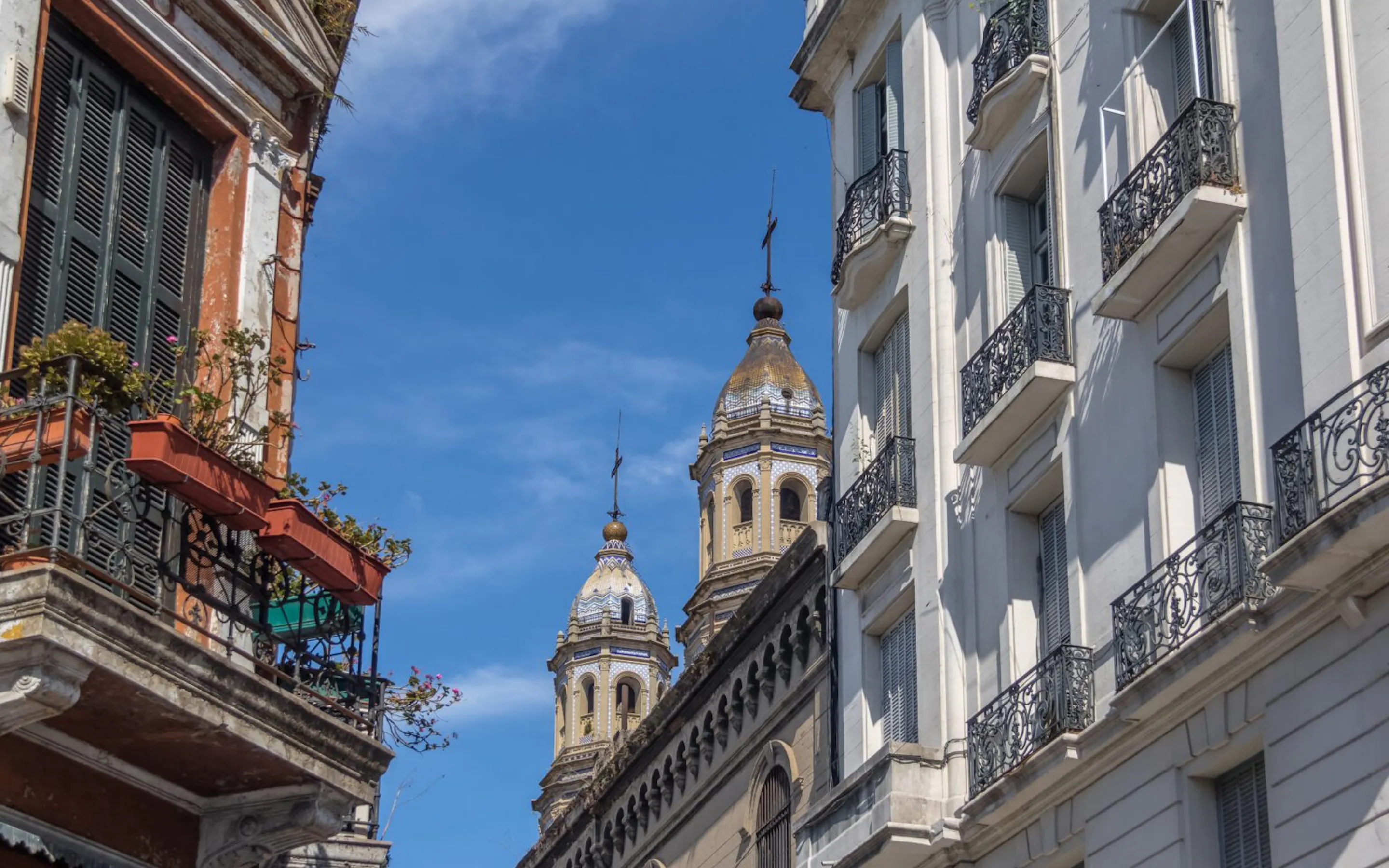 San Pedro Telmo Church rises between pastel buildings in Buenos Aires, seen from a narrow cobbled street below.
