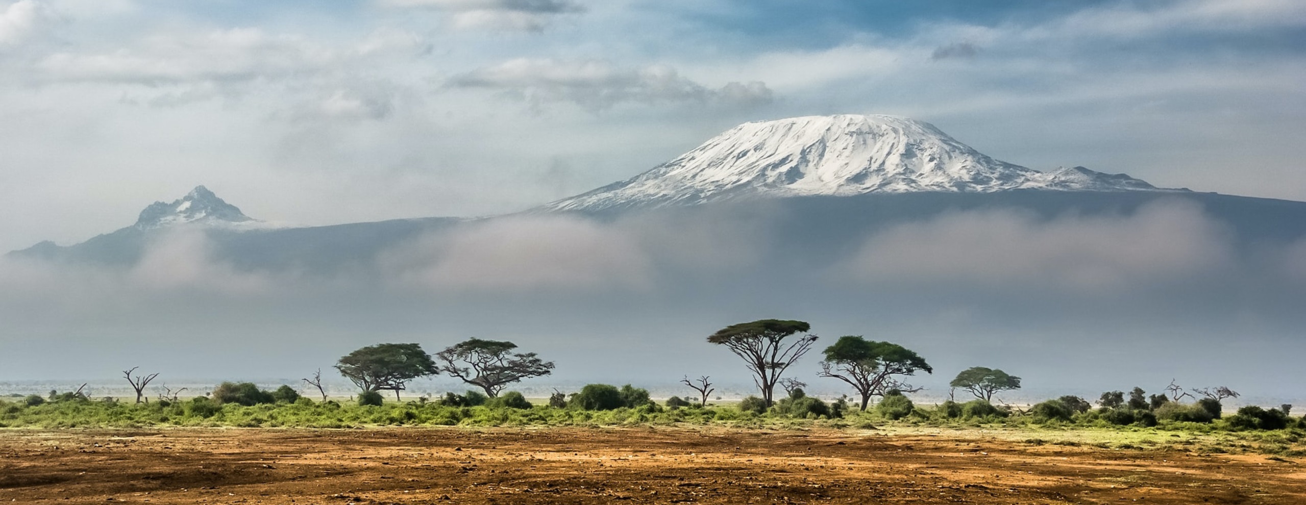 Mount Kenya rising above golden plains in Kenya's Laikipia, under expansive skies beneath dramatic skies.