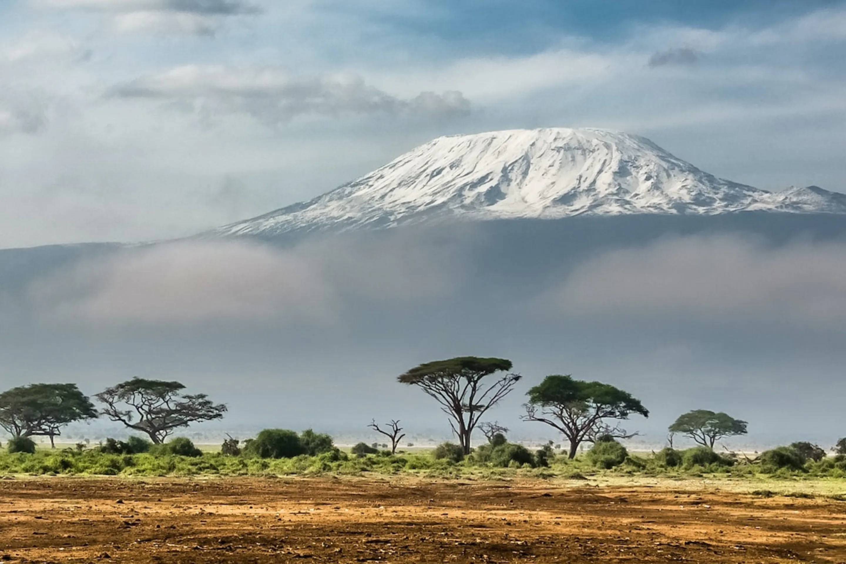 Mount Kenya rising above golden plains in Kenya's Laikipia, under expansive skies beneath dramatic skies.