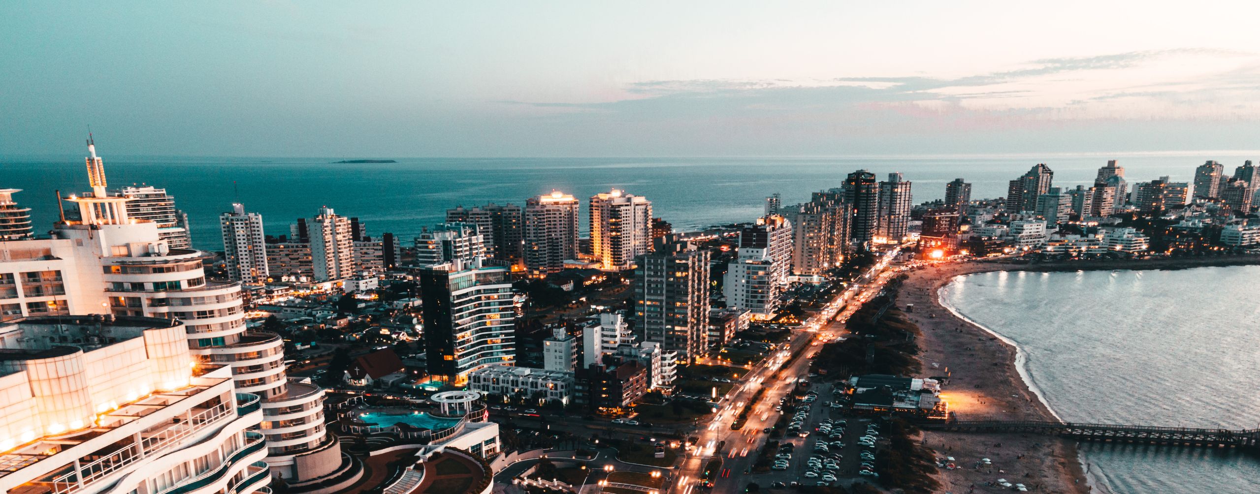 Montevideo's skyline stretches along the Rio de la Plata, with curving shoreline and evening lights by the water.