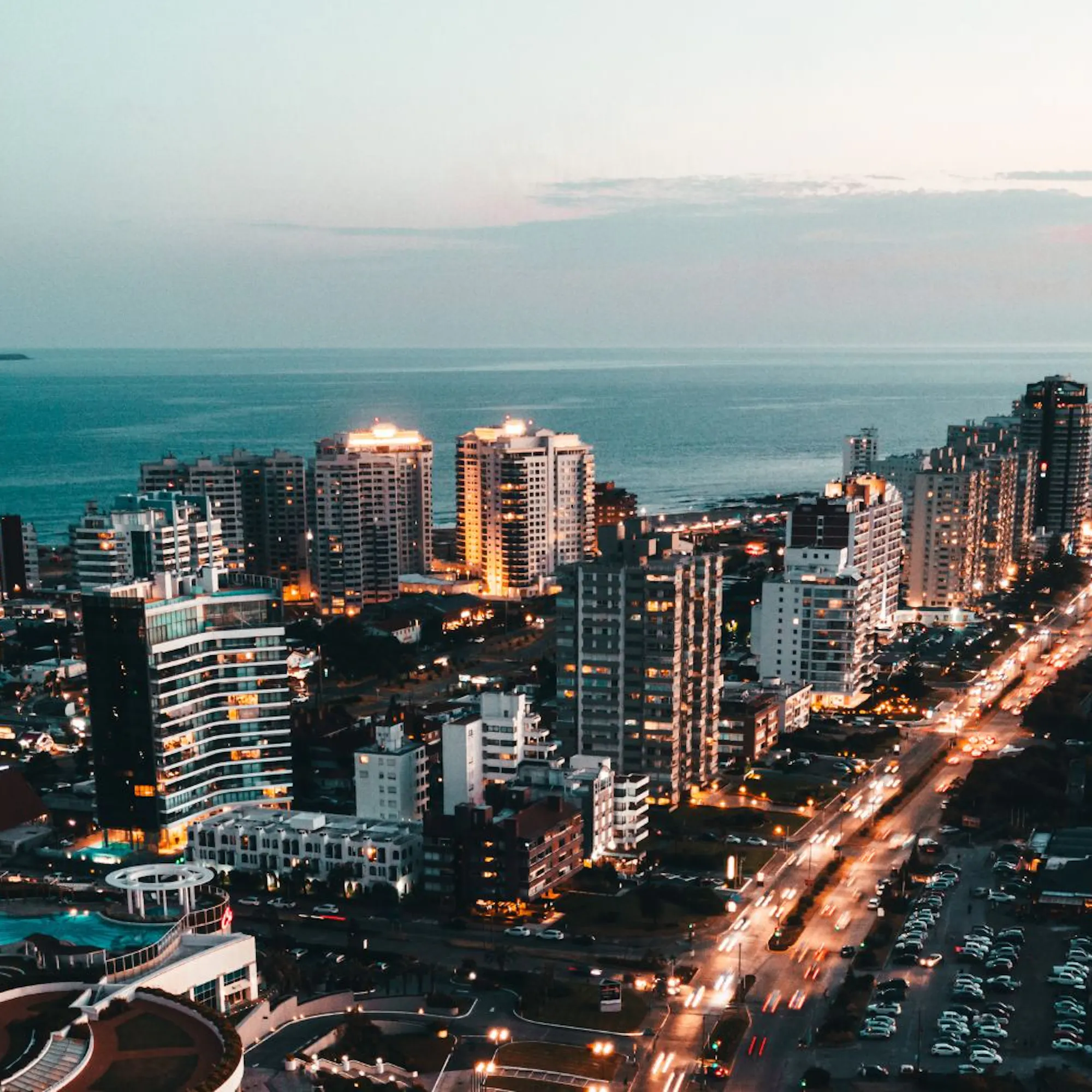 Montevideo's skyline stretches along the Rio de la Plata, with curving shoreline and evening lights by the water.