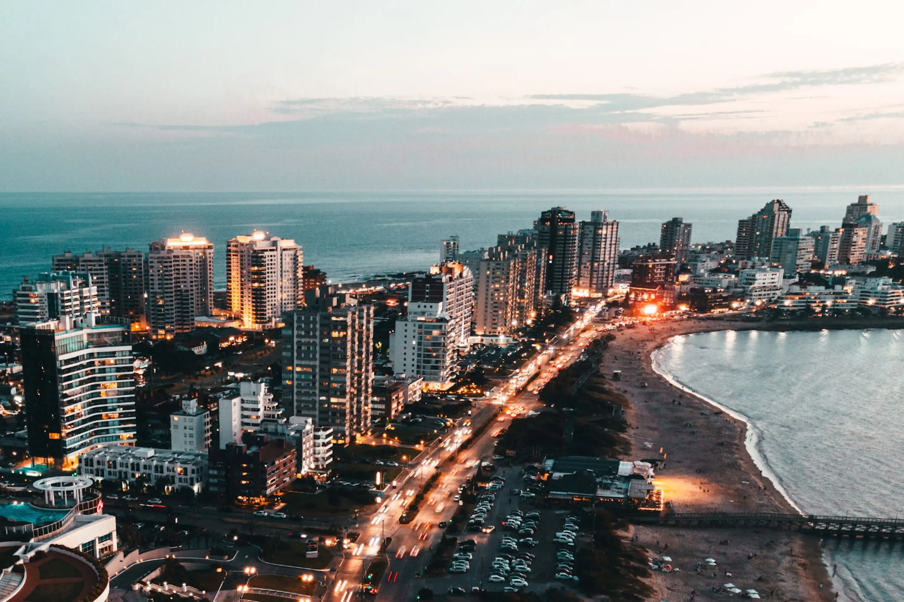 Montevideo's skyline stretches along the Rio de la Plata, with curving shoreline and evening lights by the water.