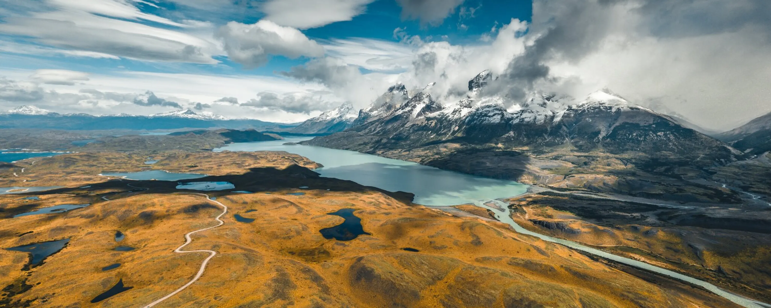 Jagged peaks rise above a Patagonian valley and lake near El Chalten, with rocky slopes cutting into the sky.