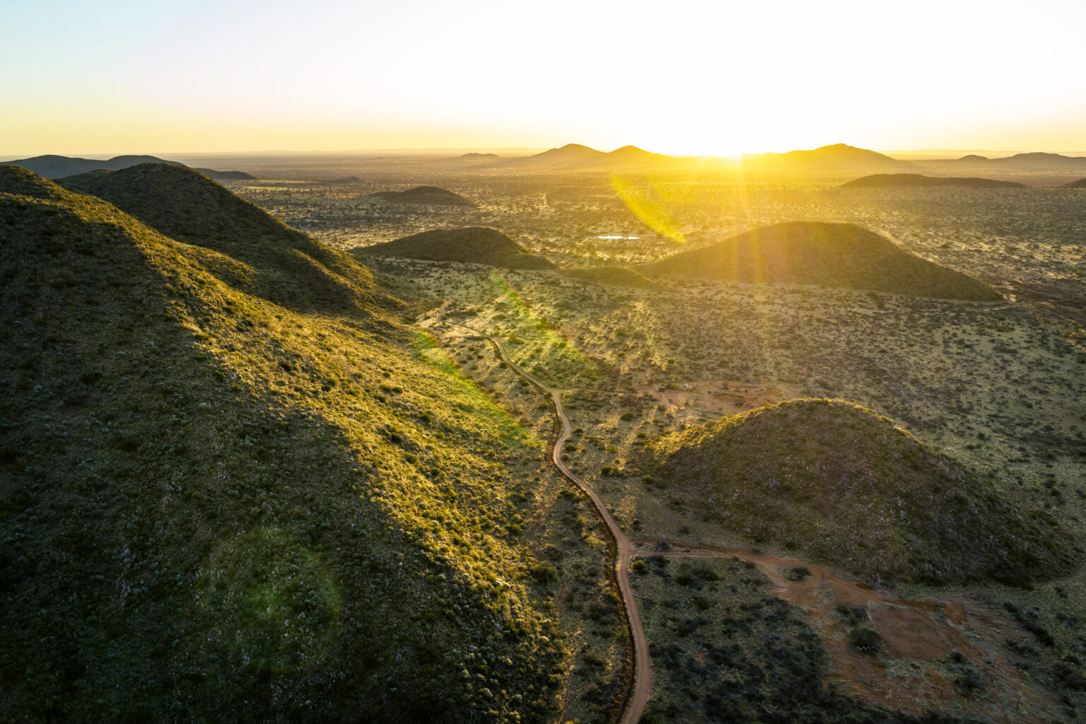 A tented camp sits beneath mountains at Loapi in South Africa's Southern Kalahari, with open ground in front.