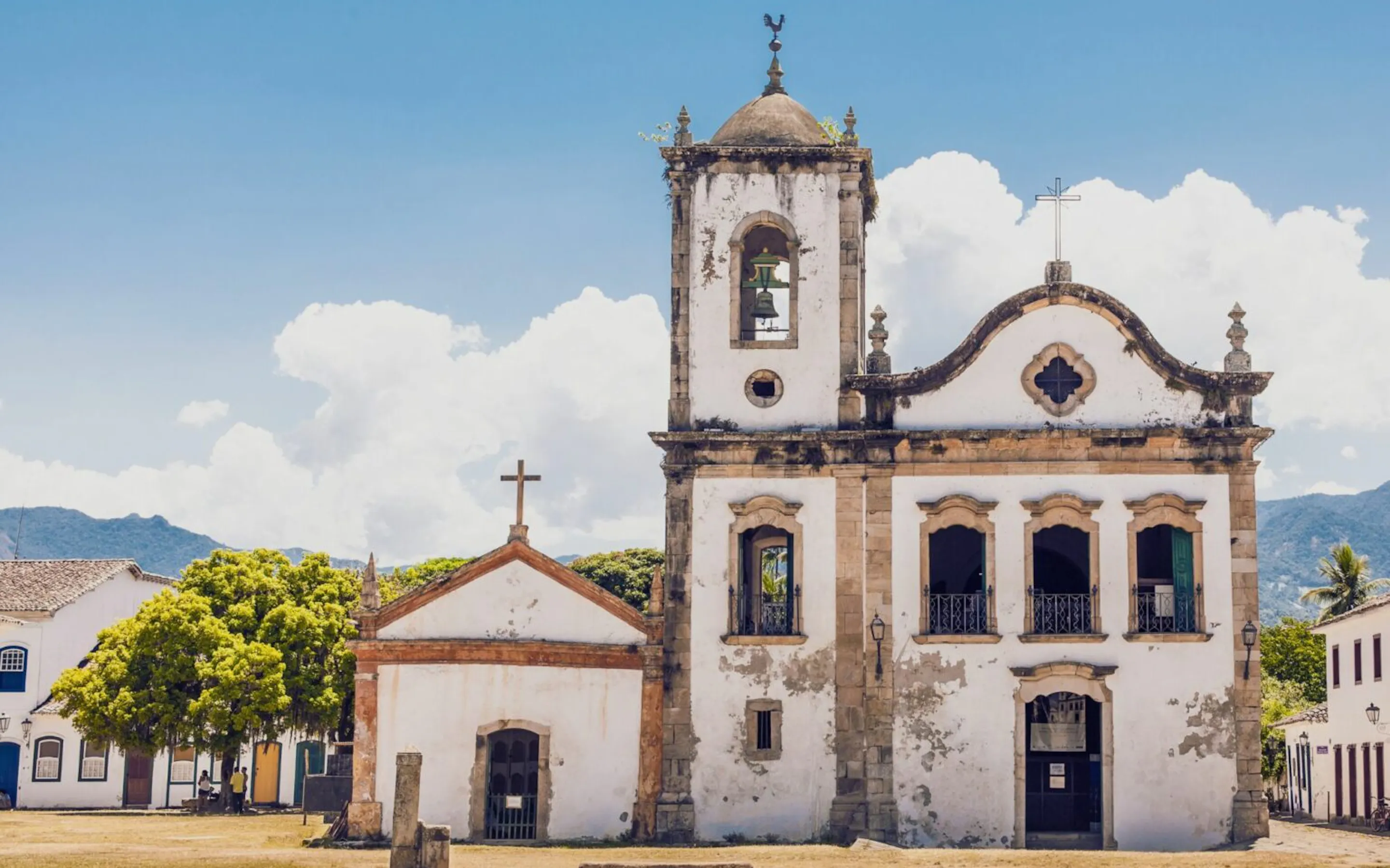 Paraty's whitewashed church stands against a blue sky, with quiet streets and colonial facades around the square.