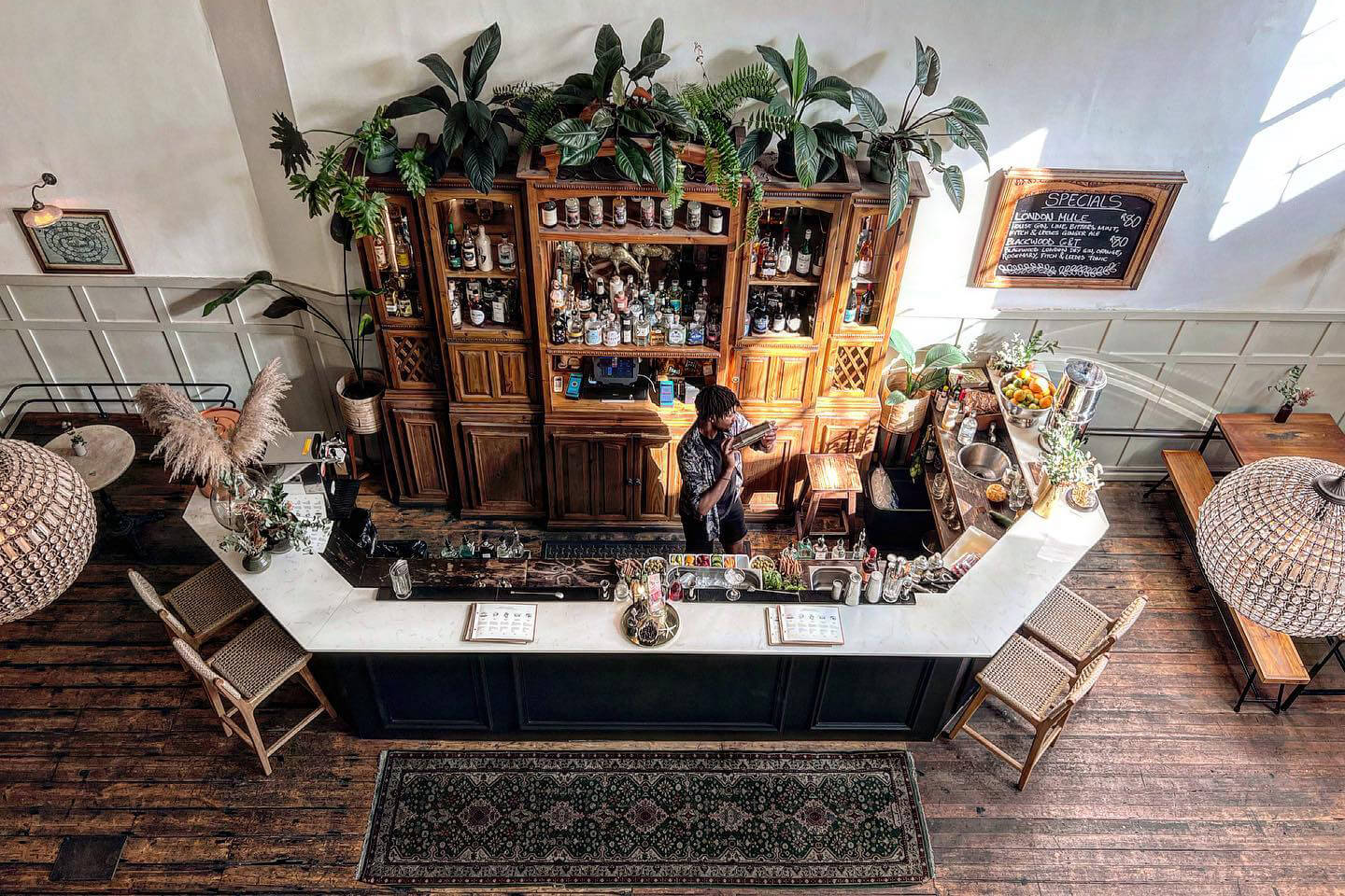 An intimate cocktail bar at The Gin Bar in Cape Town features shelves, bottles, and warm light on the walls.