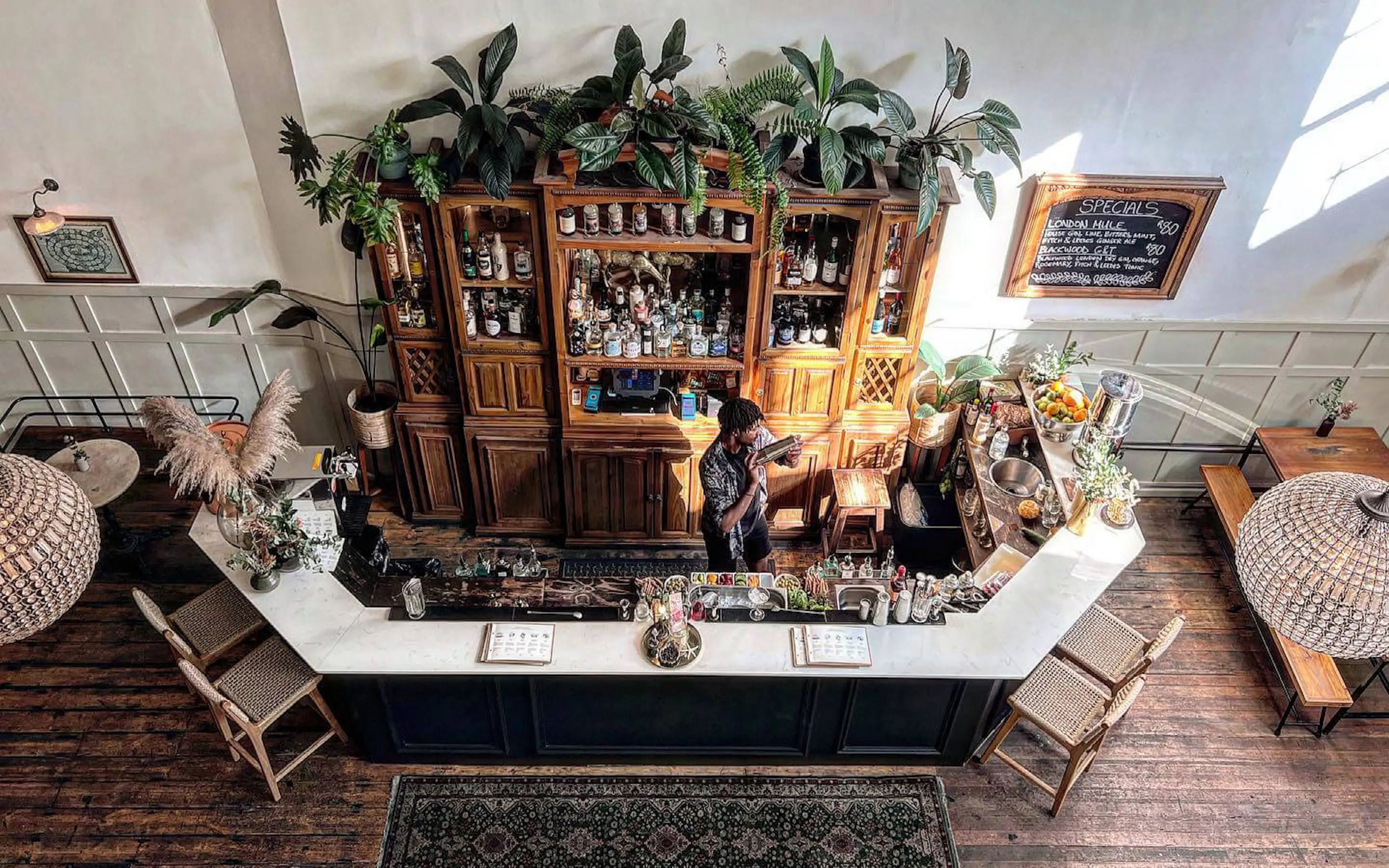 An intimate cocktail bar at The Gin Bar in Cape Town features shelves, bottles, and warm light on the walls.