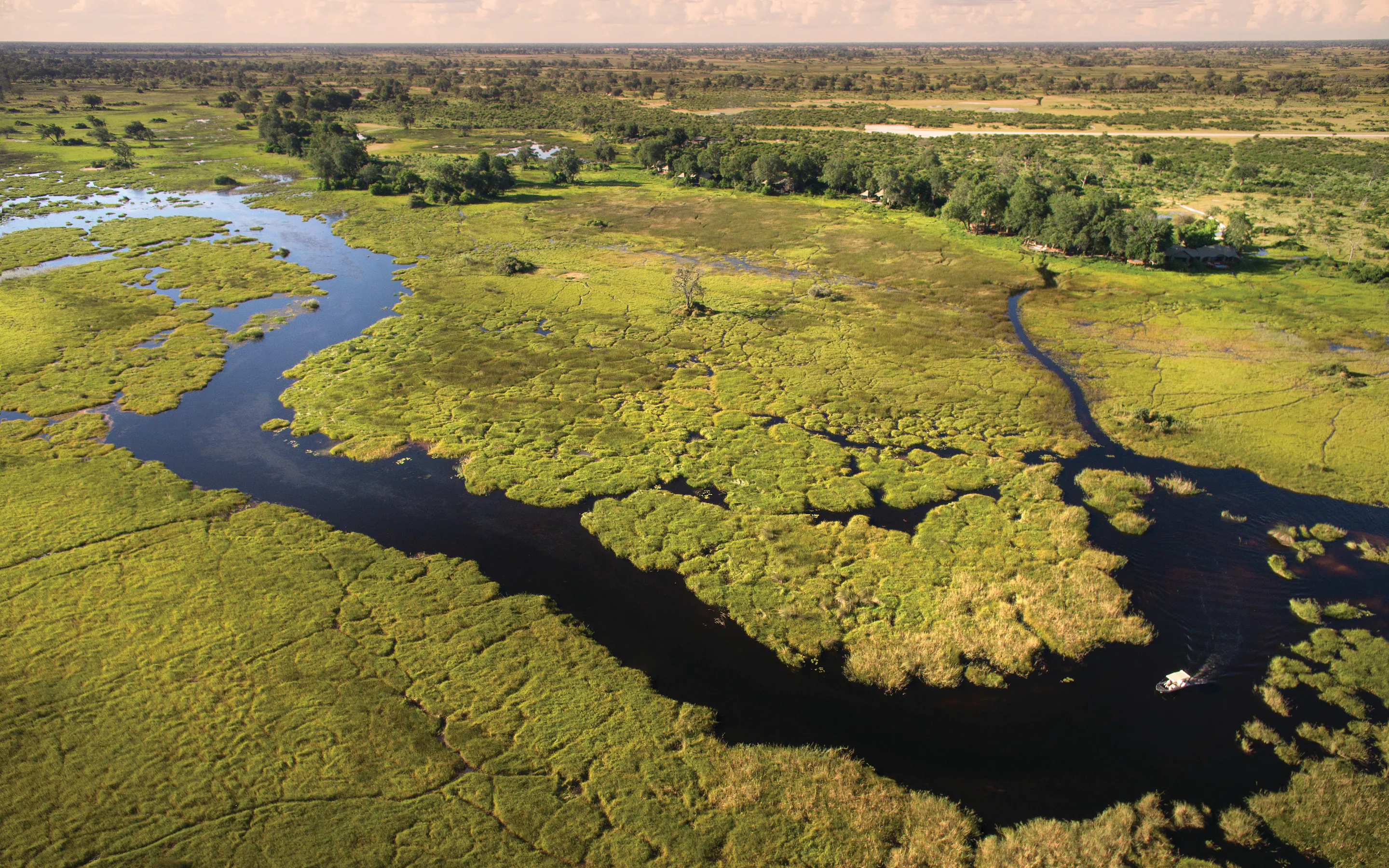 An aerial view looks over Duba Plains Camp waterways, with winding channels and green delta islands below.