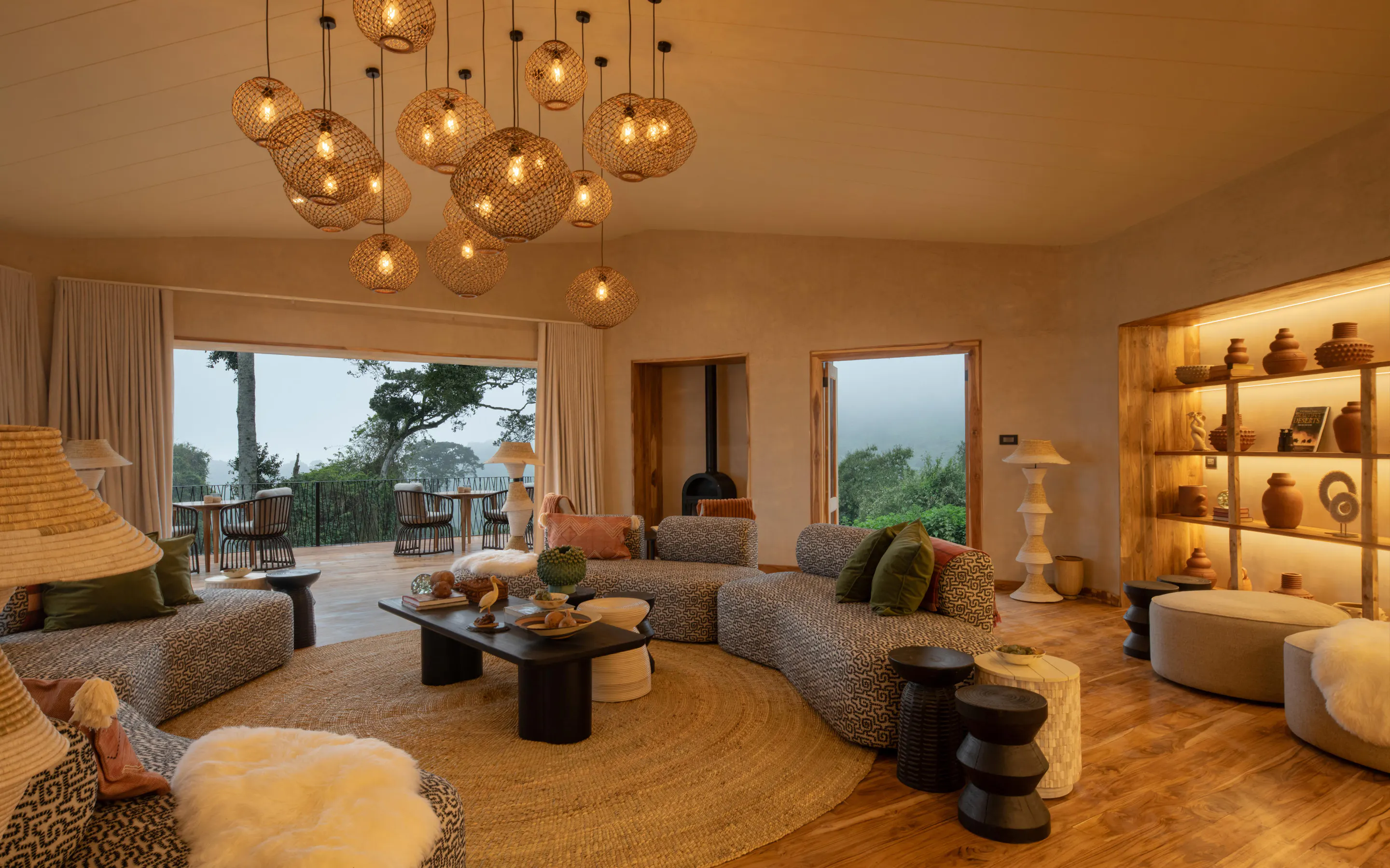 A circular lounge at Lemala Osonjoi glows warmly, with woven lights, deep sofas, and wide windows to the hills.