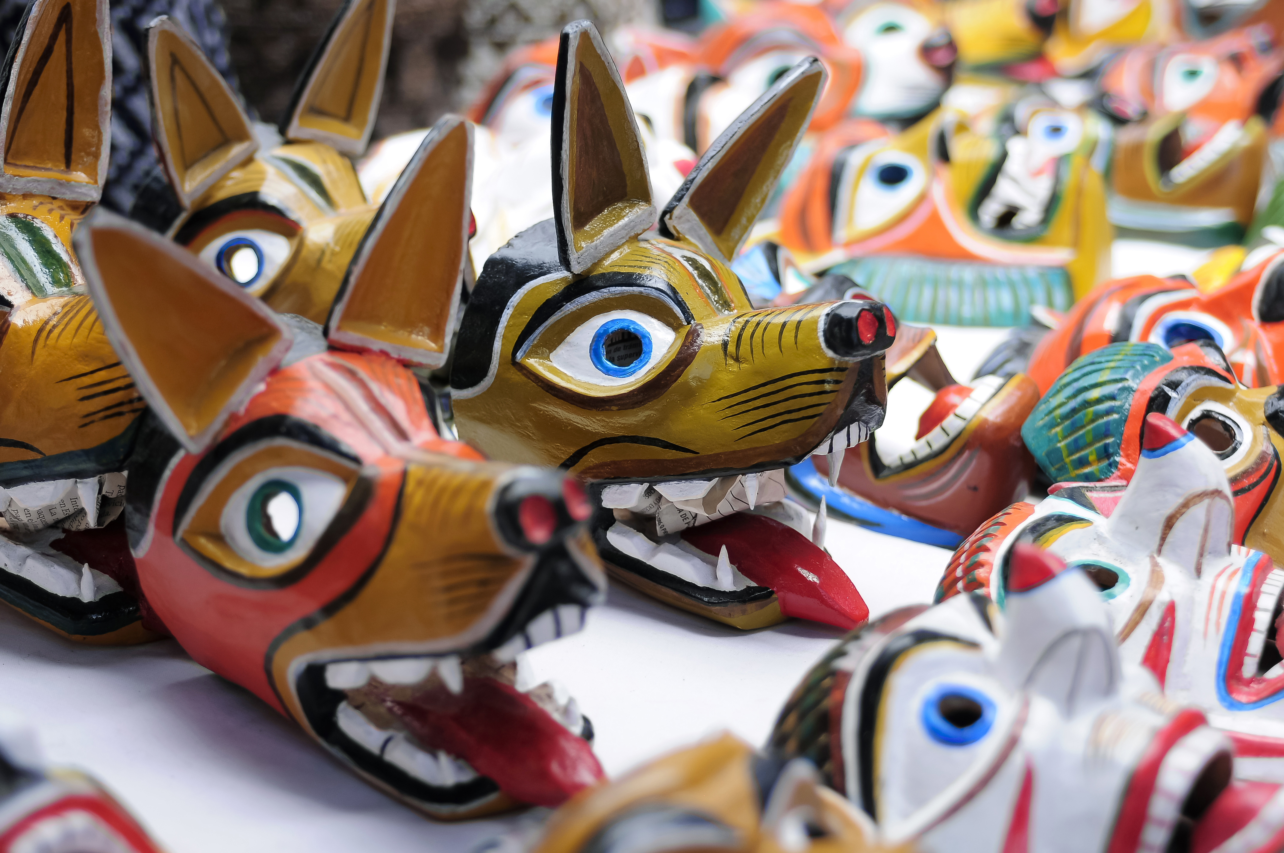Rows of colorful handcrafted wolf masks line a market stall, highlighting traditional folk art in Otavalo, Ecuador.