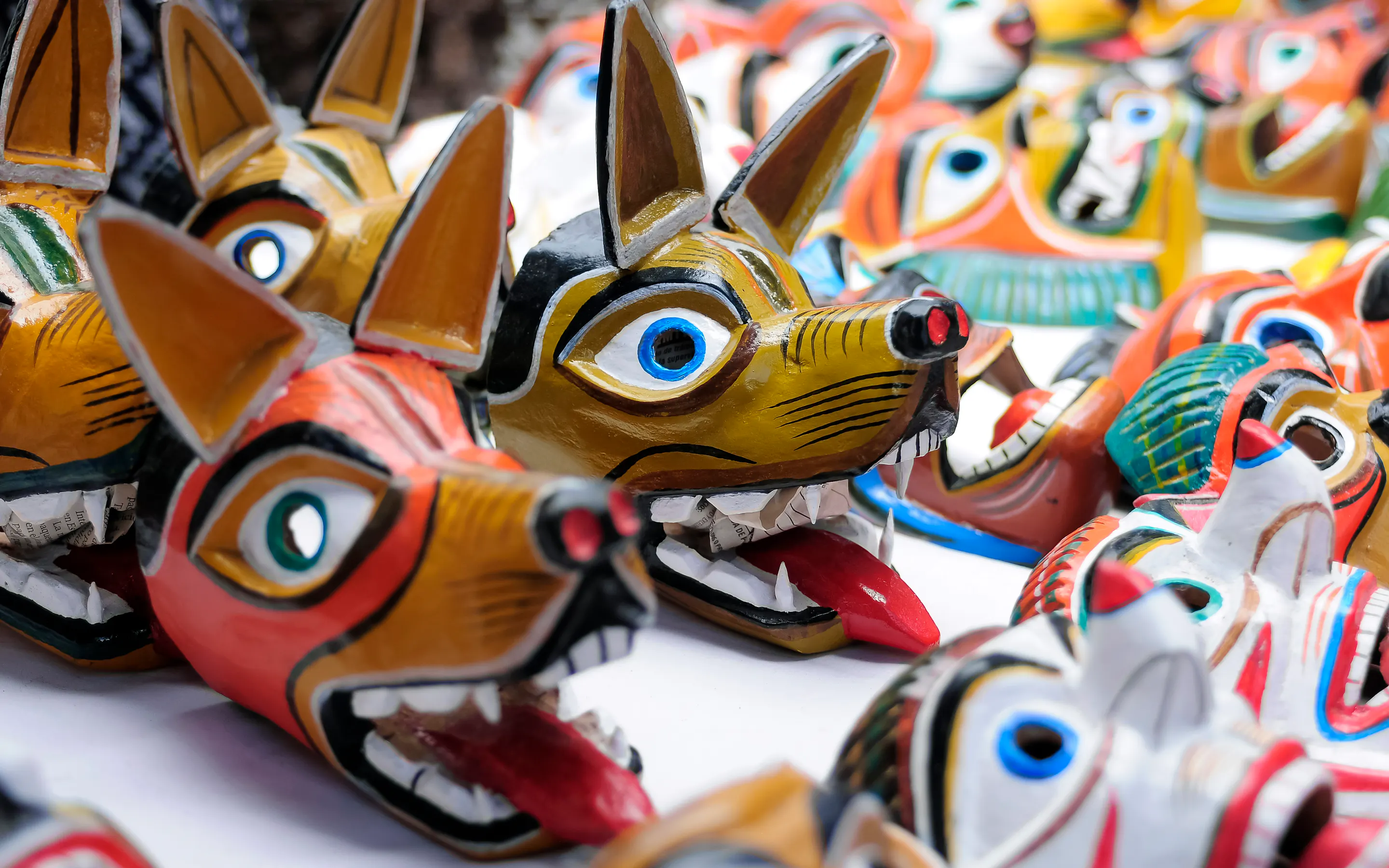 Rows of colorful handcrafted wolf masks line a market stall, highlighting traditional folk art in Otavalo, Ecuador.