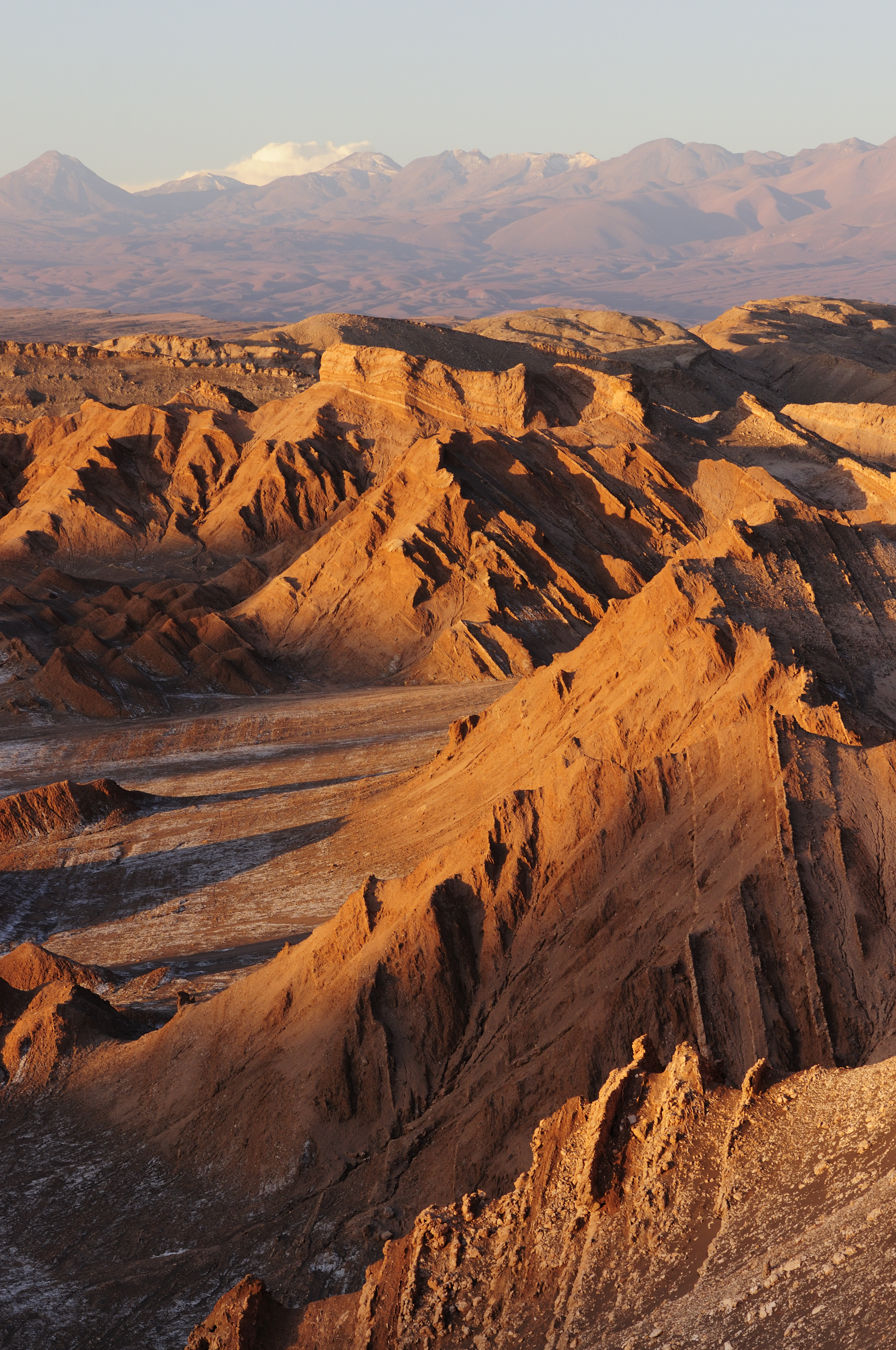 Ridges glow in late light above the Valley of the Moon, where dry red slopes fold toward distant mountains.