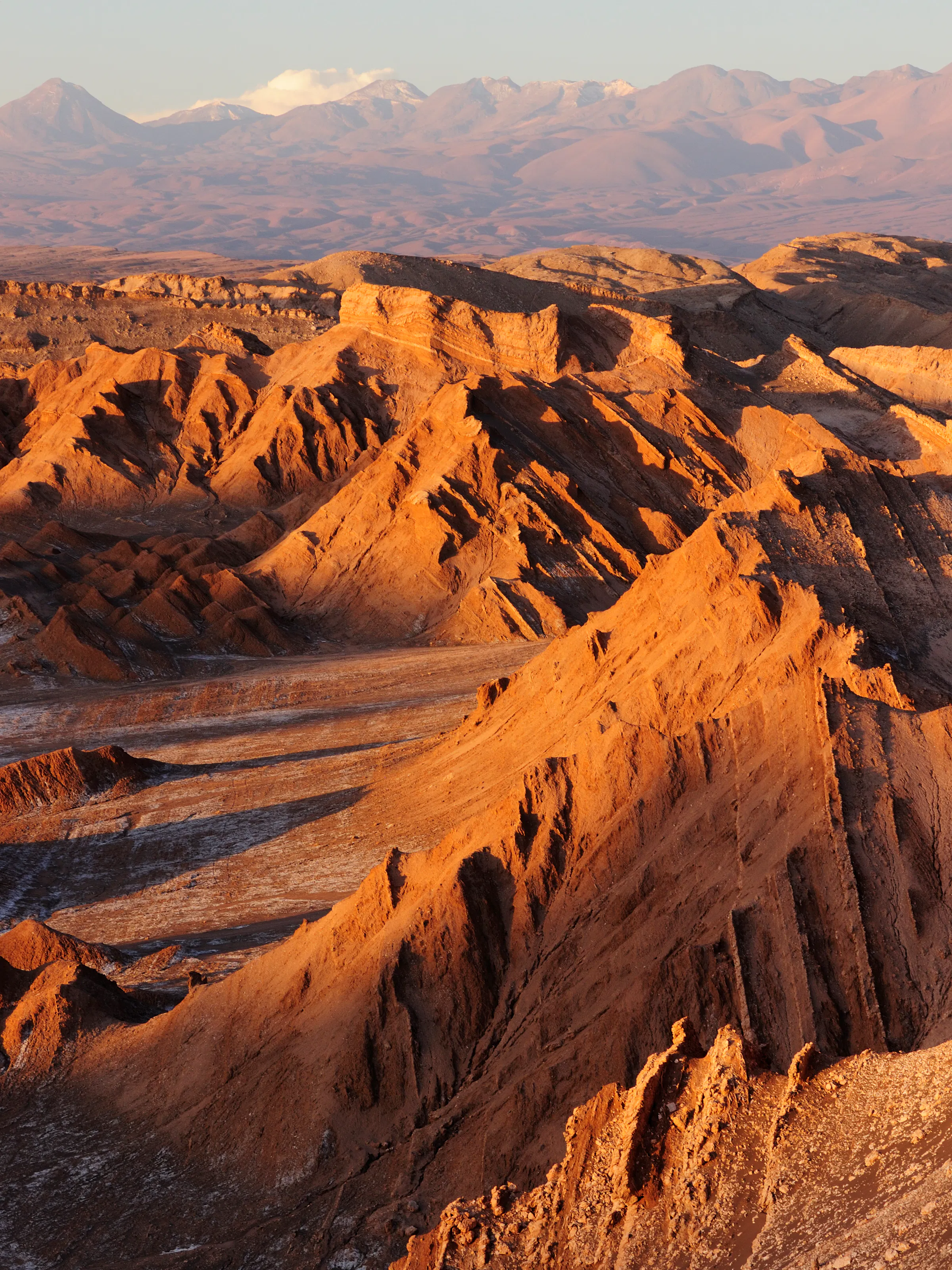 Ridges glow in late light above the Valley of the Moon, where dry red slopes fold toward distant mountains.