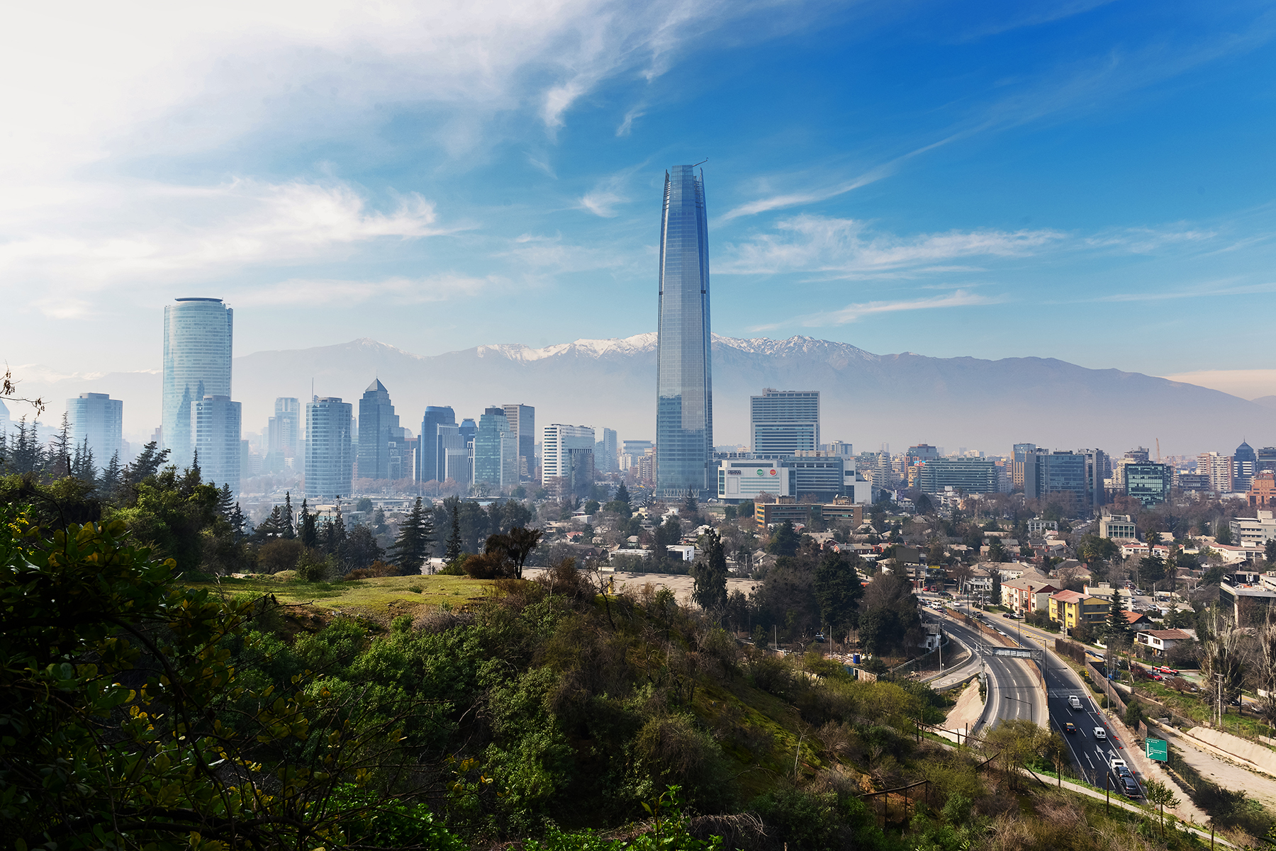 Santiago's skyline rises beyond San Cristobal Hill, with the Gran Torre and mountains visible through morning haze.