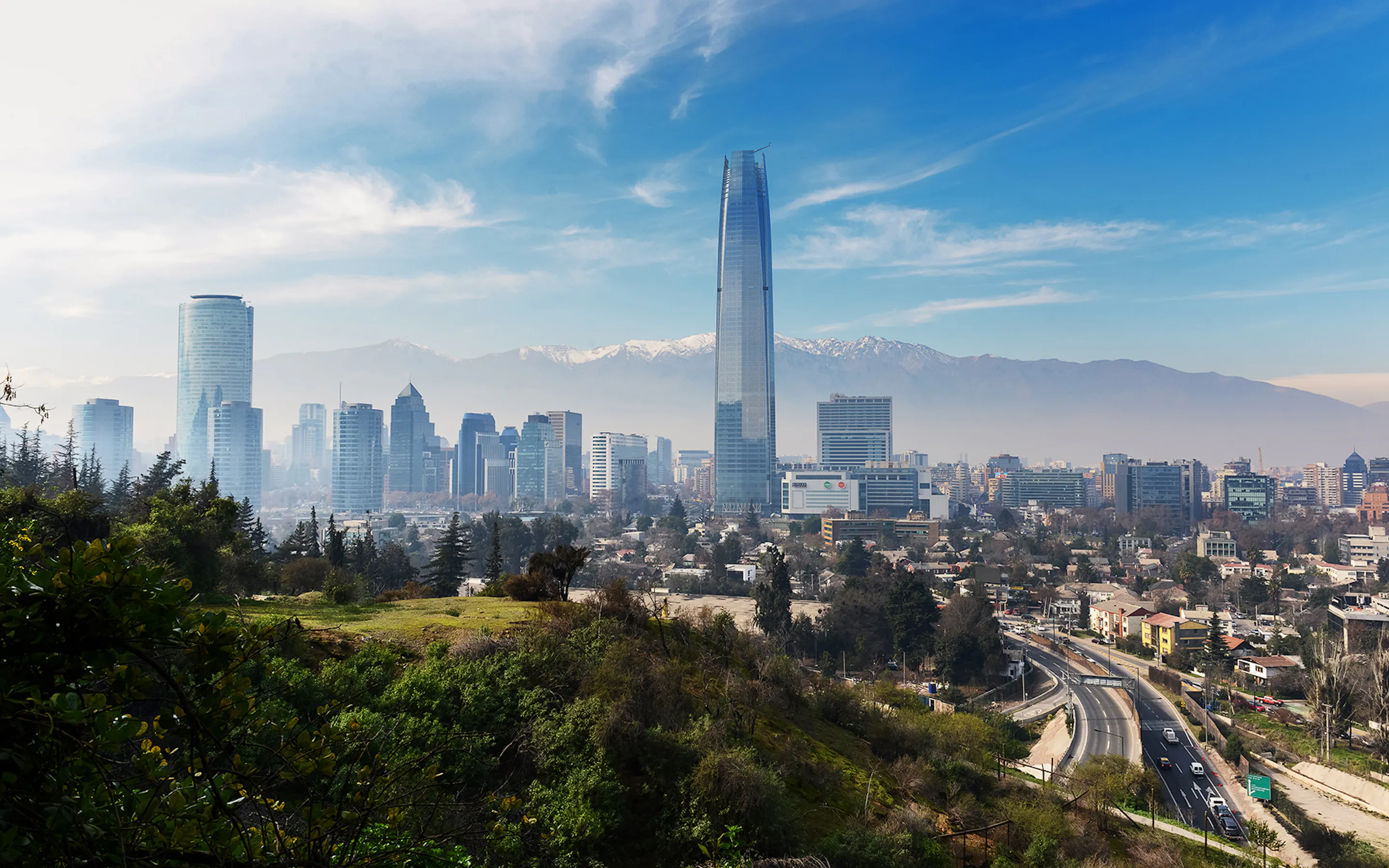 Santiago's skyline rises beyond San Cristobal Hill, with the Gran Torre and mountains visible through morning haze.
