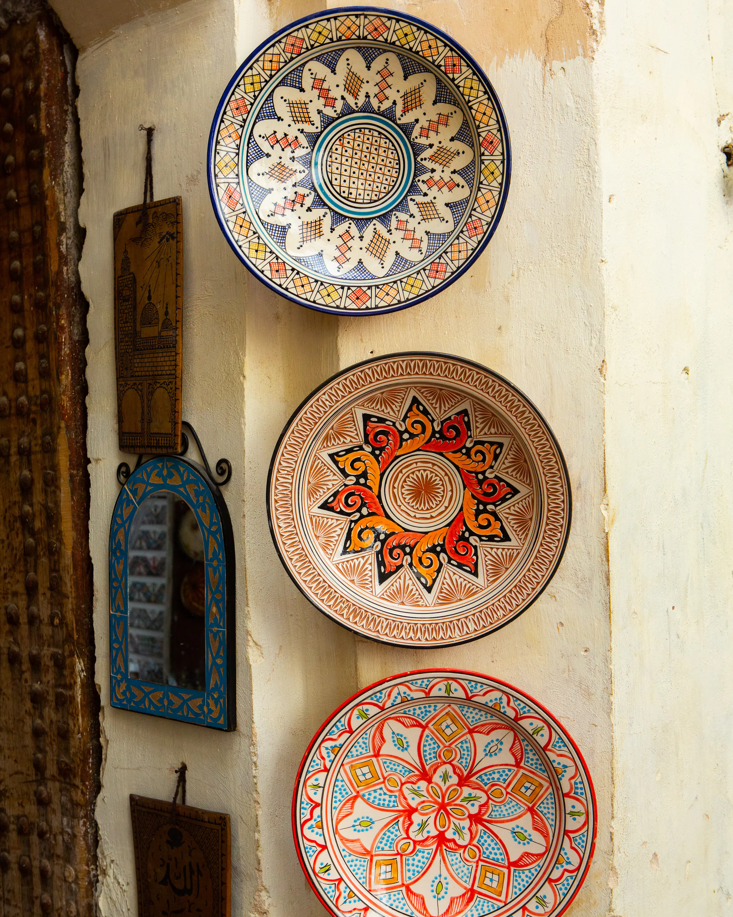 Colorful hand-painted ceramic plates displayed on a wall in a narrow alley.