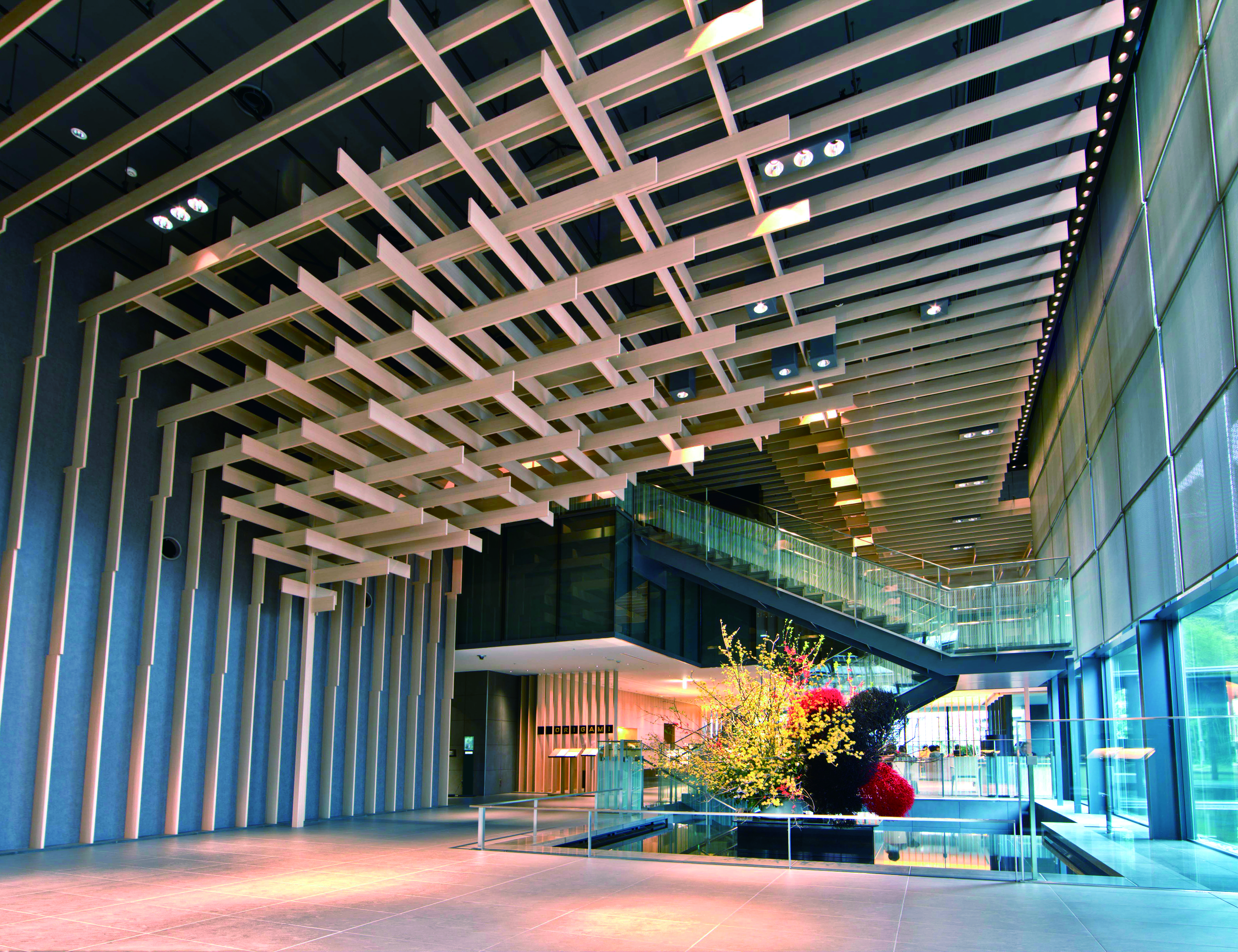 The Capitol Hotel Tokyu lobby pairs a sculptural timber ceiling with glass walls, stairs, and a bright floral display.