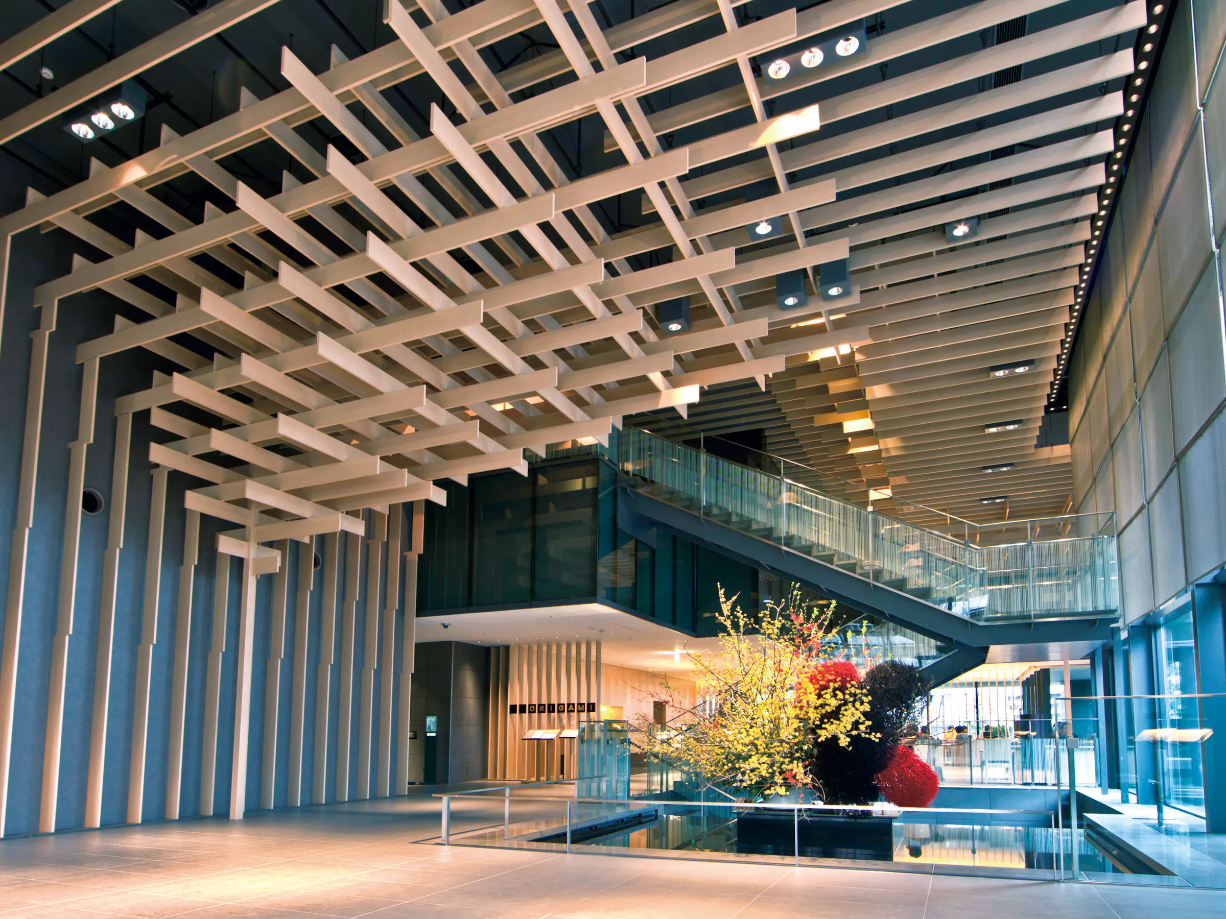 The Capitol Hotel Tokyu lobby pairs a sculptural timber ceiling with glass walls, stairs, and a bright floral display.