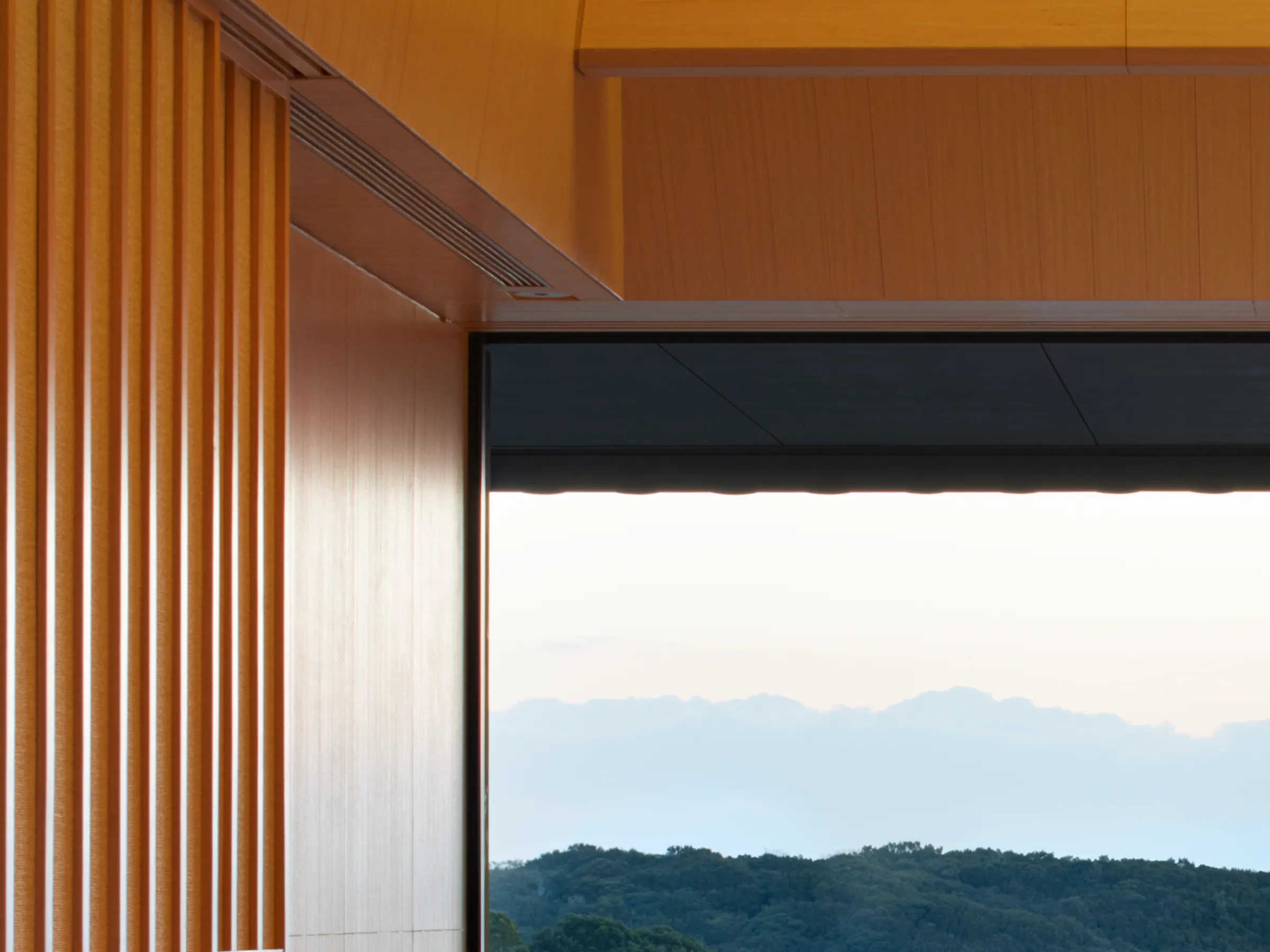 A bright Nagi Suite bedroom at Amanemu opens to bay views, with woven walls, a daybed, and a broad terrace beyond.