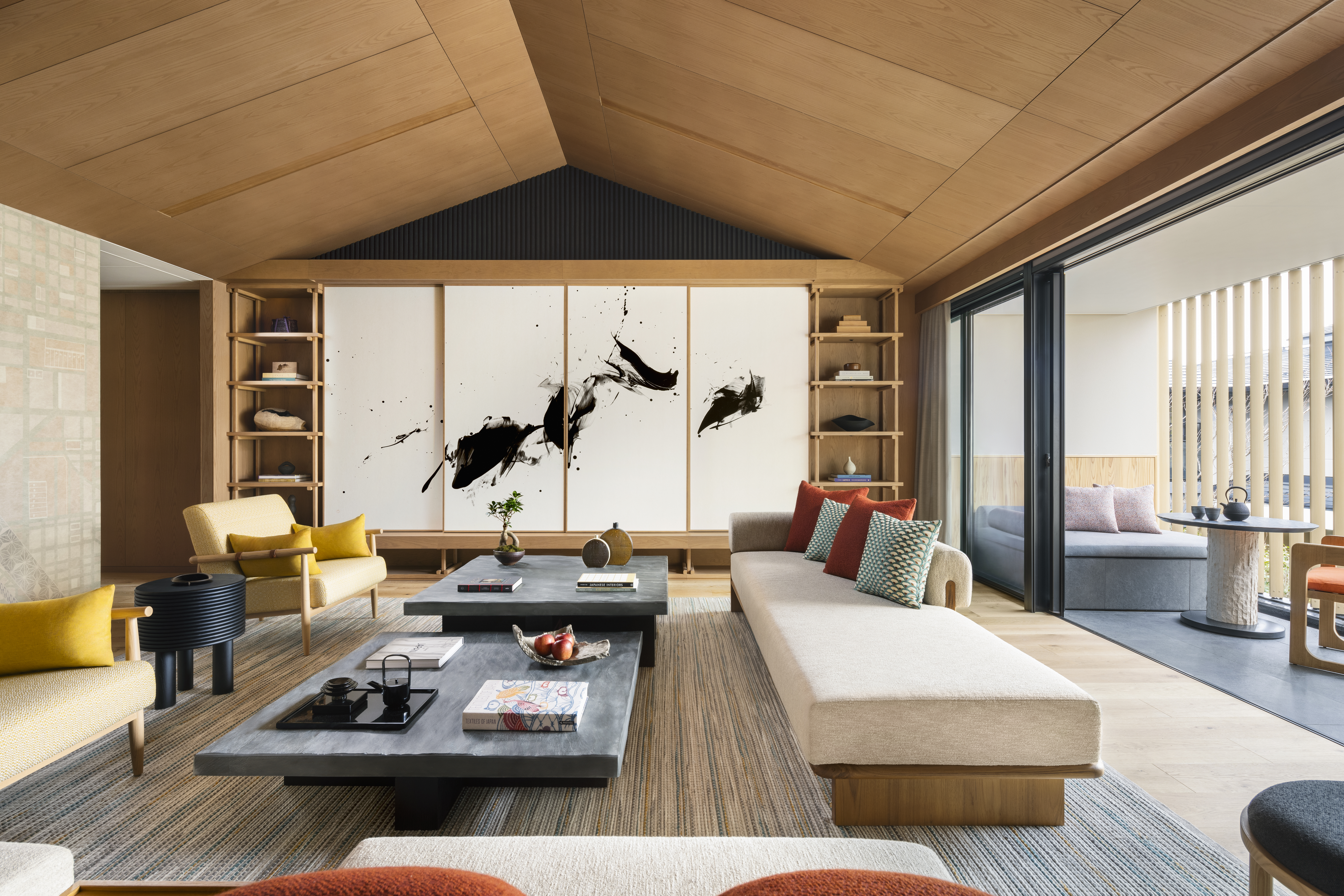 A serene living room at Six Senses Kyoto features low tables, pale wood, bold artwork, and a covered terrace beyond.