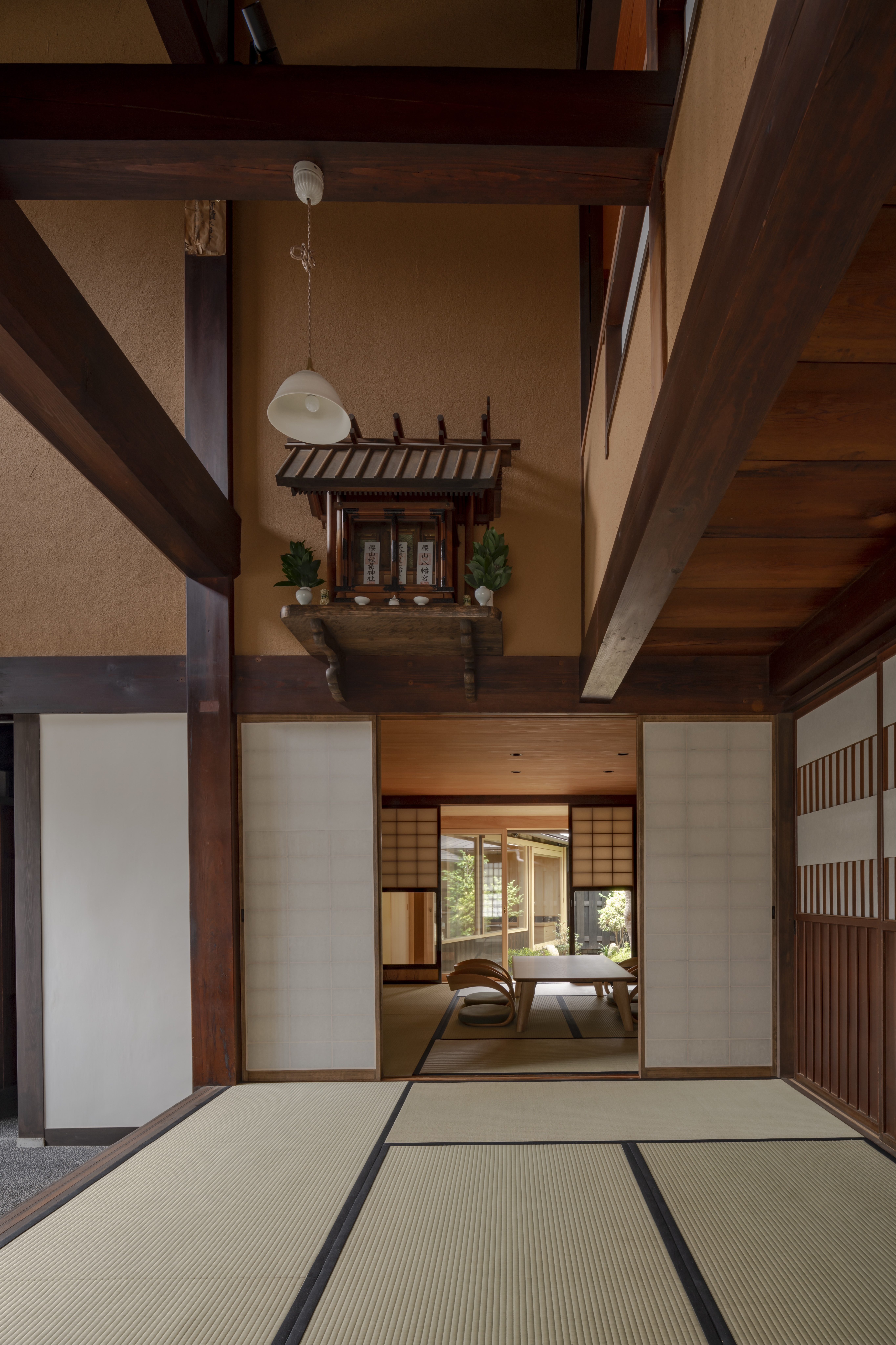 A tatami room at TANIYA in Takayama features exposed beams, sliding shoji, a wooden table, and a kamidana altar.