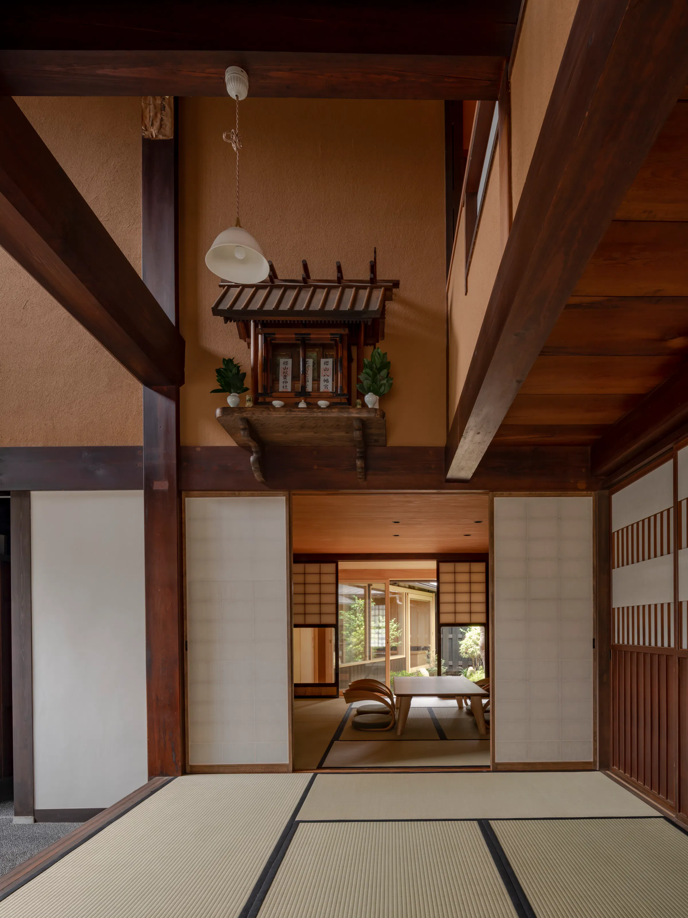 A tatami room at TANIYA in Takayama features exposed beams, sliding shoji, a wooden table, and a kamidana altar.