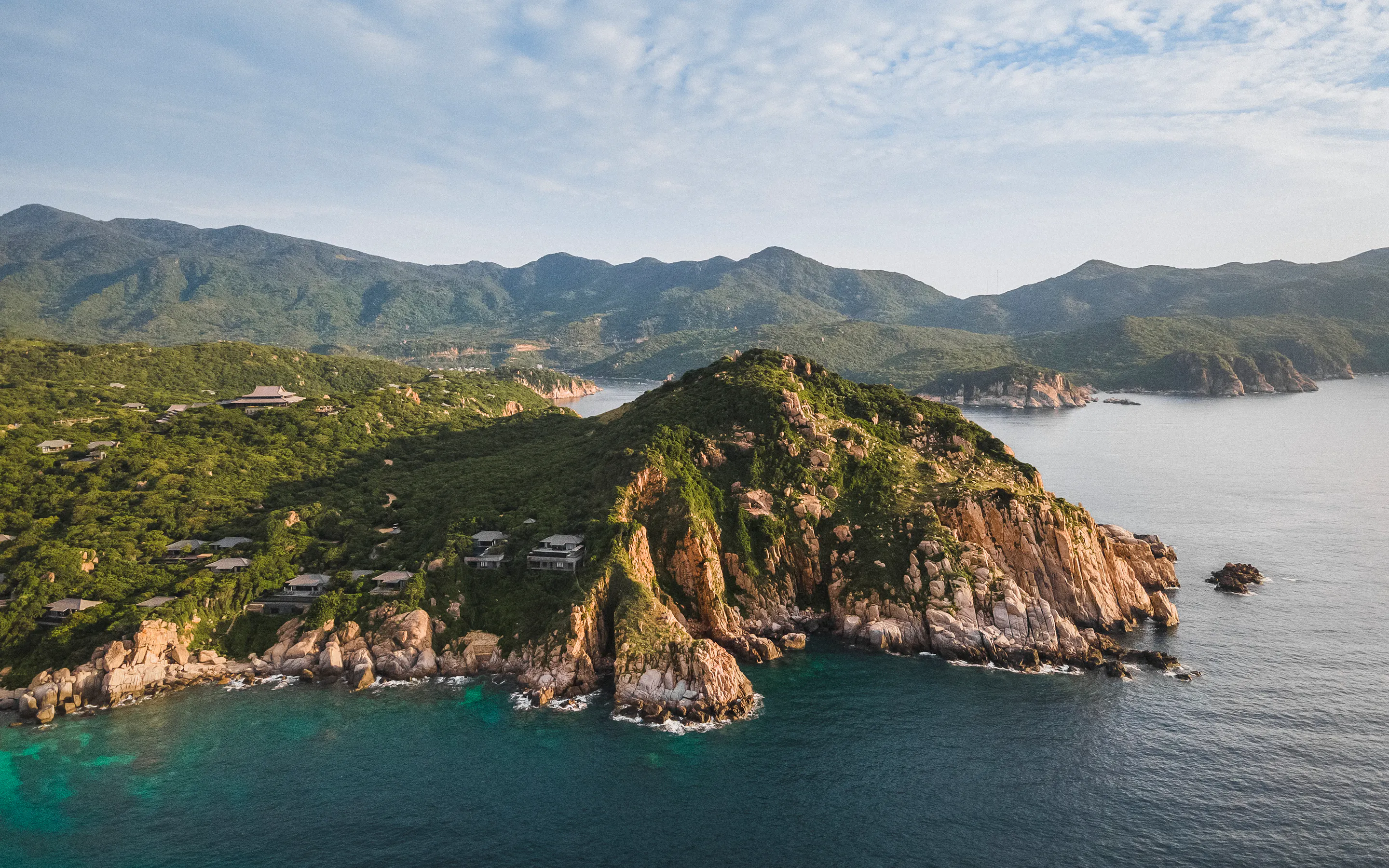 An aerial view shows Amanoi villas set among rocky green hills above a calm bay on Vietnam's south-central coast.