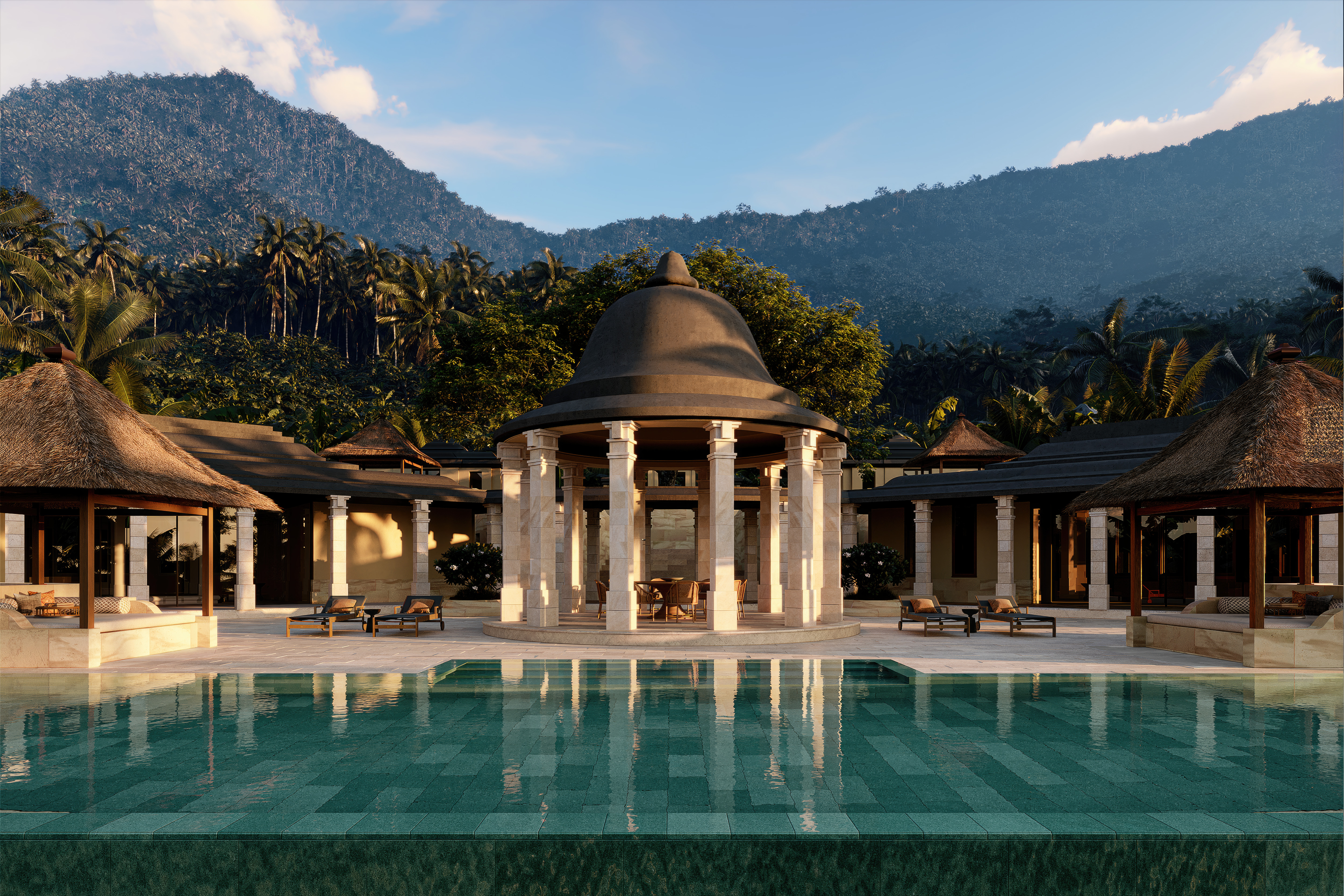 Amanjiwo's stone pavilion rises beyond a long pool, with forested hills and palm-lined slopes behind the residence.