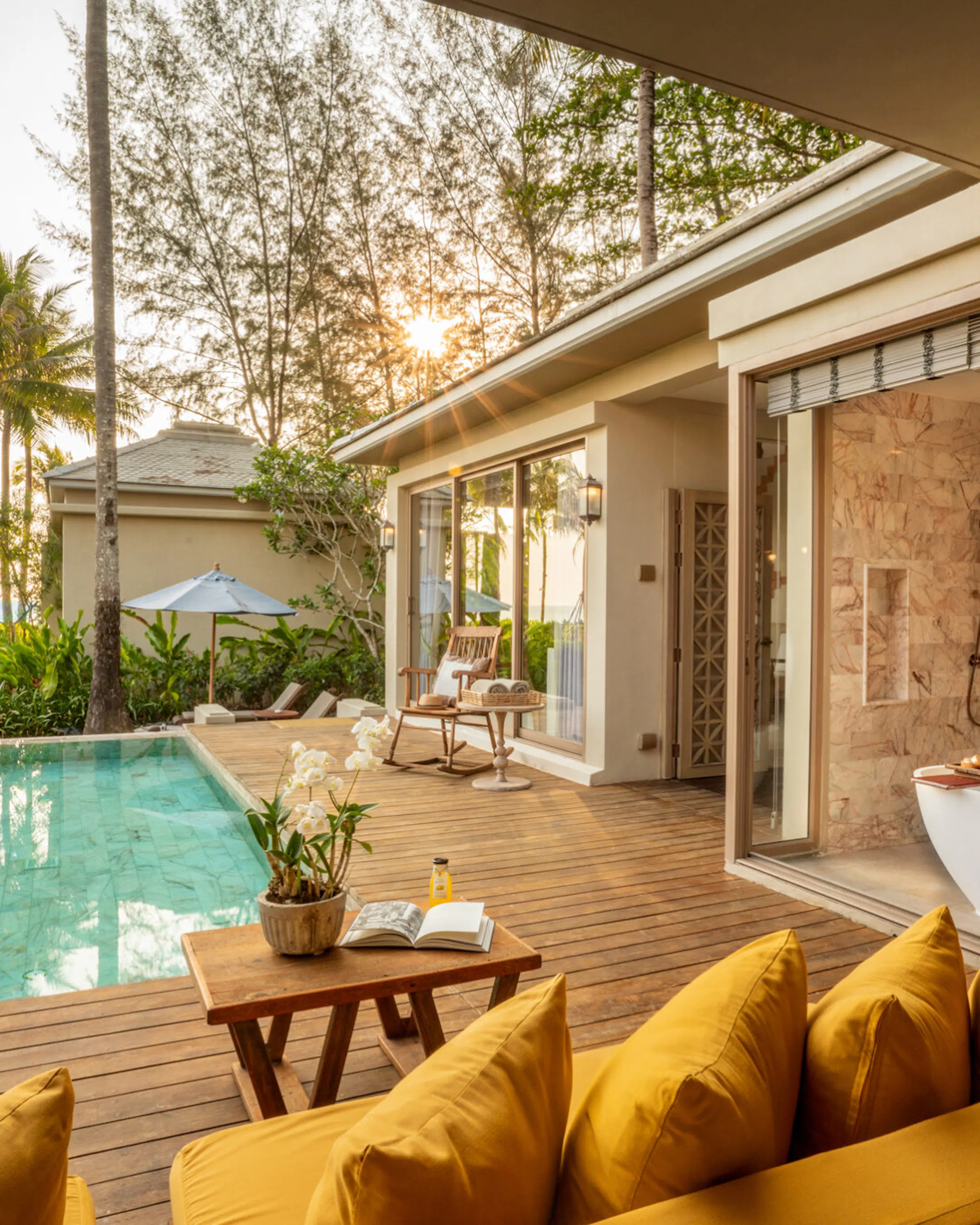 A private pool and open-air bath sit beside a bright villa at Devasom Khao Lak, framed by palms and soft sunlight.