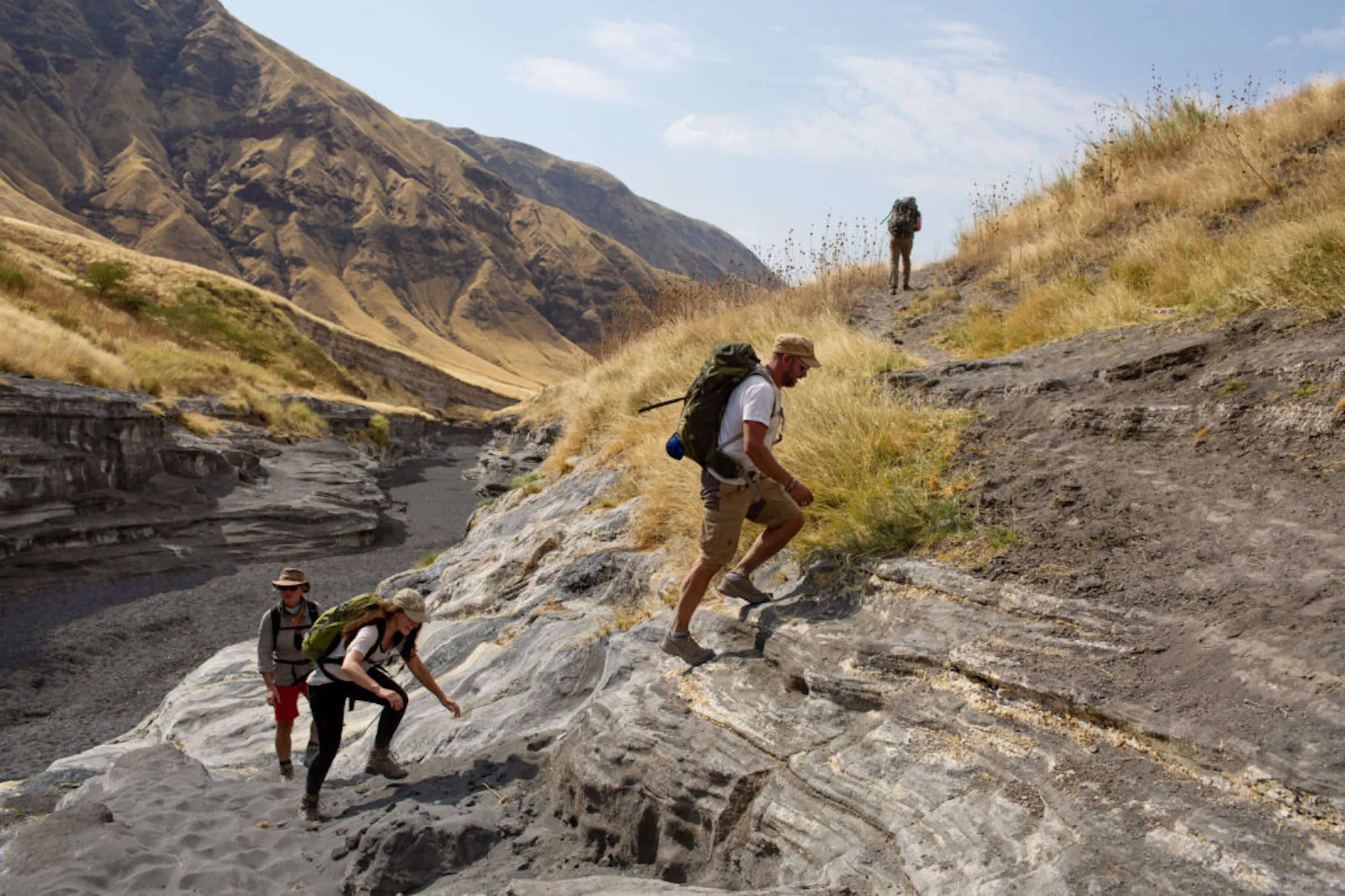 Four hikers climb a steep hill in the Great Rift Valley.