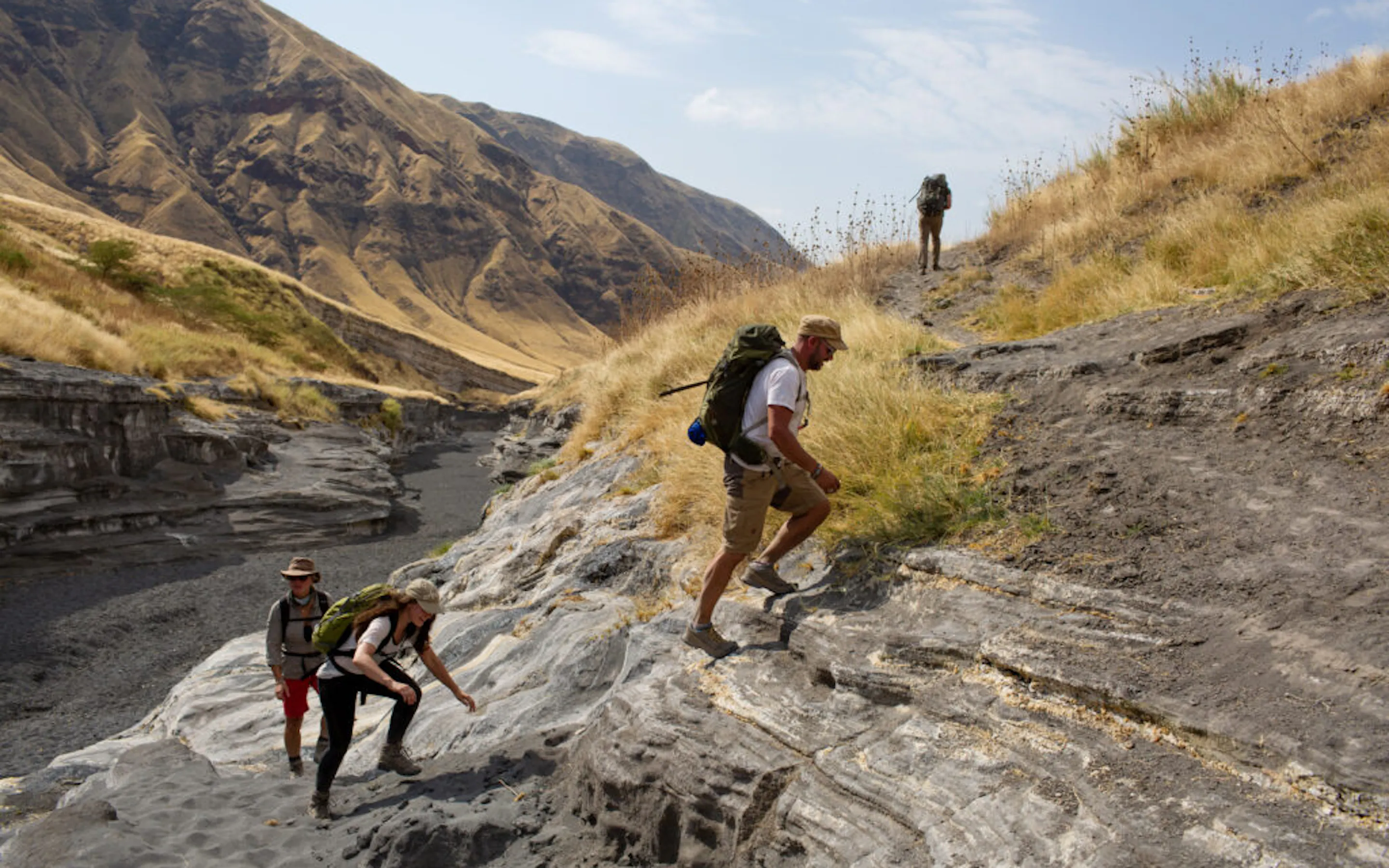 Four hikers climb a steep hill in the Great Rift Valley.