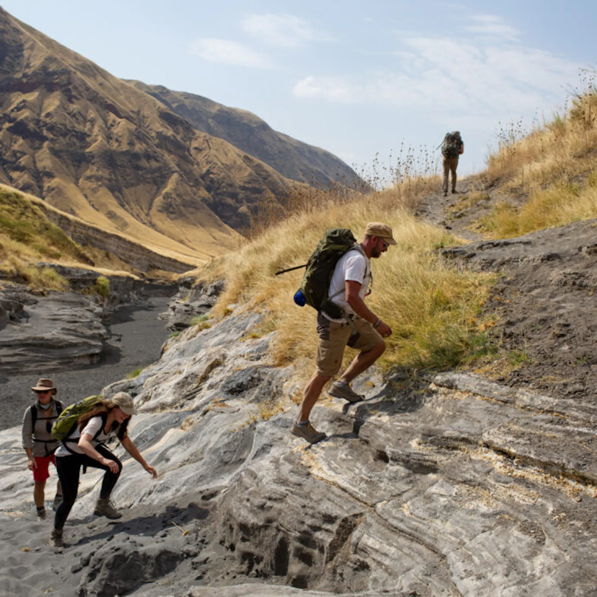 Four hikers climb a steep hill in the Great Rift Valley.