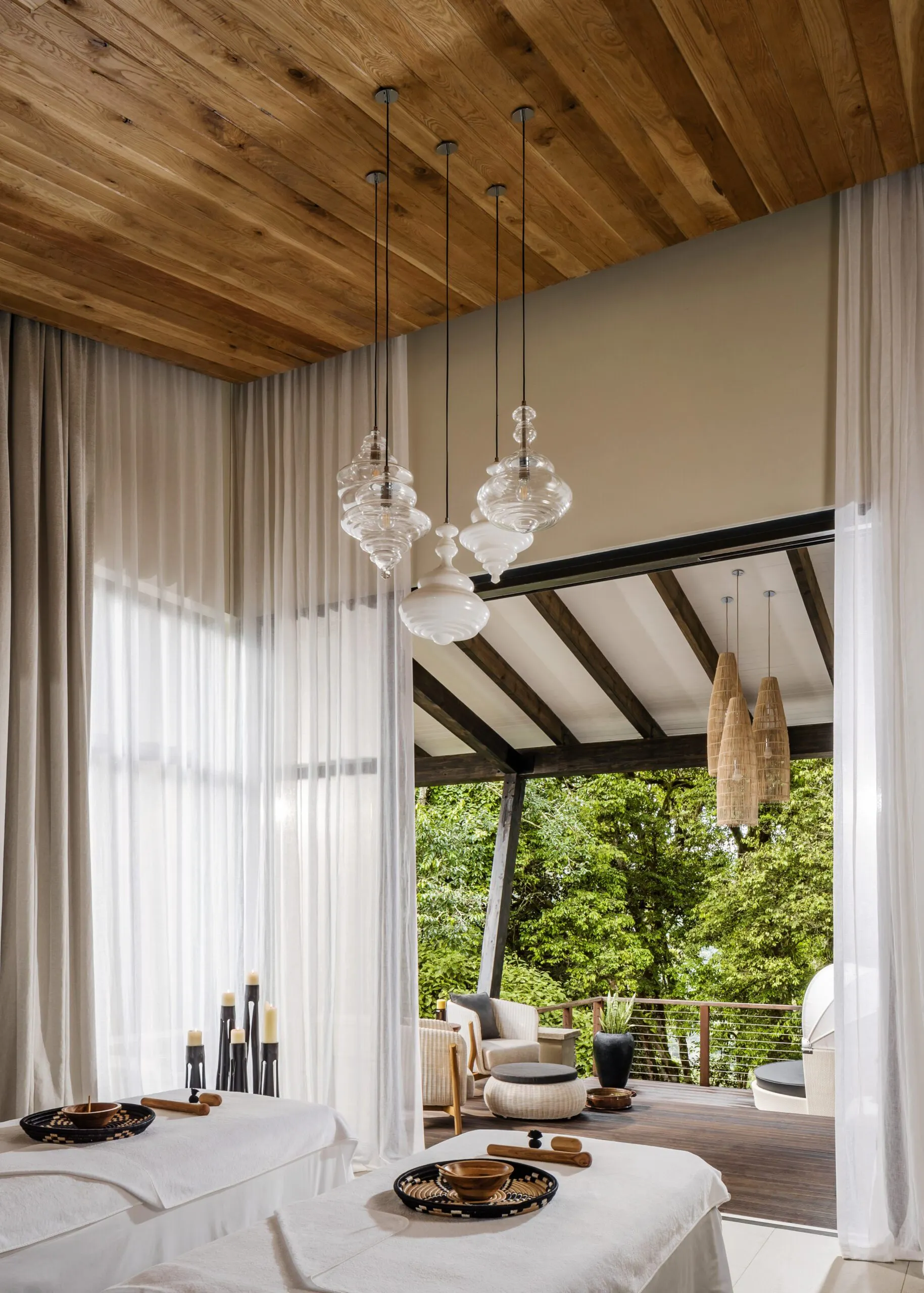 A bright spa room at One&Only Nyungwe House opens to forest views, with a treatment bed and lounge in Rwanda.