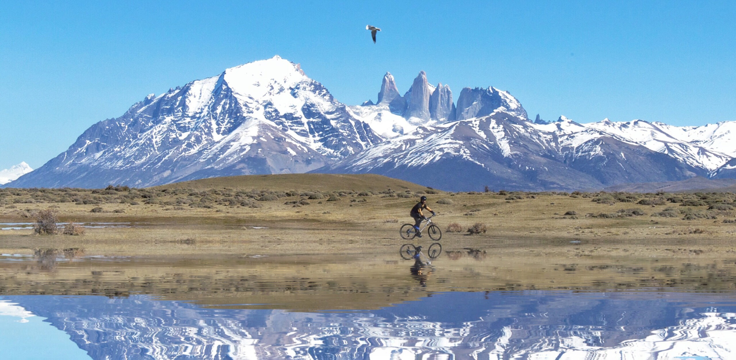 A rder cycles across open grassland near the mountains at Awasi Patagonia in Chile's Torres del Paine region.
