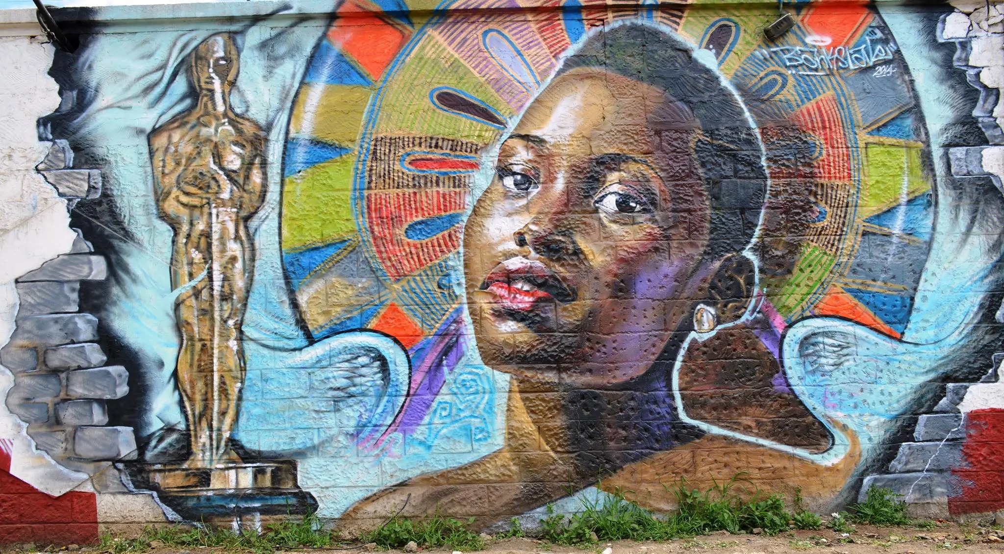 A colorful wall mural shows a portrait, wings, and a gold statue at GoDown Arts Center in Nairobi, Kenya.