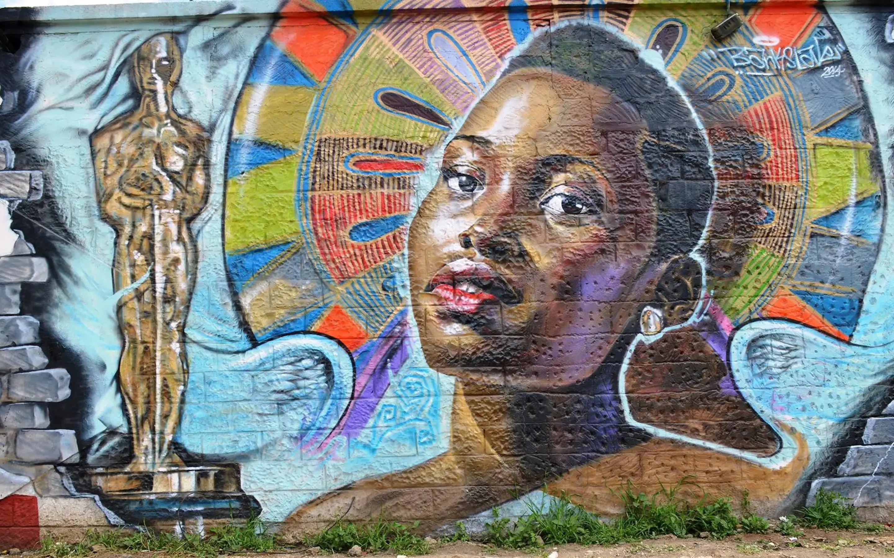 A colorful wall mural shows a portrait, wings, and a gold statue at GoDown Arts Center in Nairobi, Kenya.