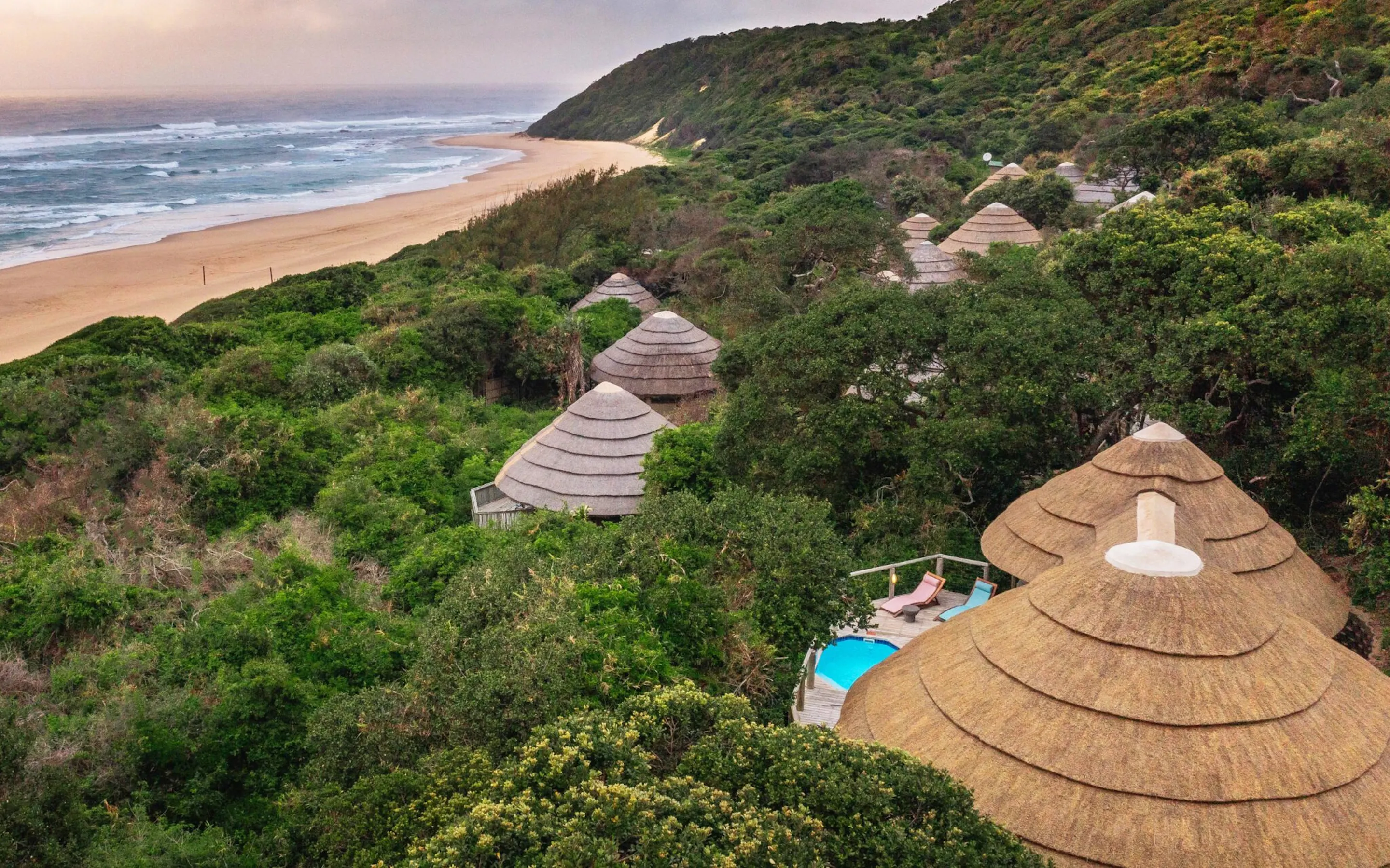 Thatched suites nestle in coastal forest above a long sandy beach at Thonga Beach Lodge in KwaZulu-Natal, South Africa.