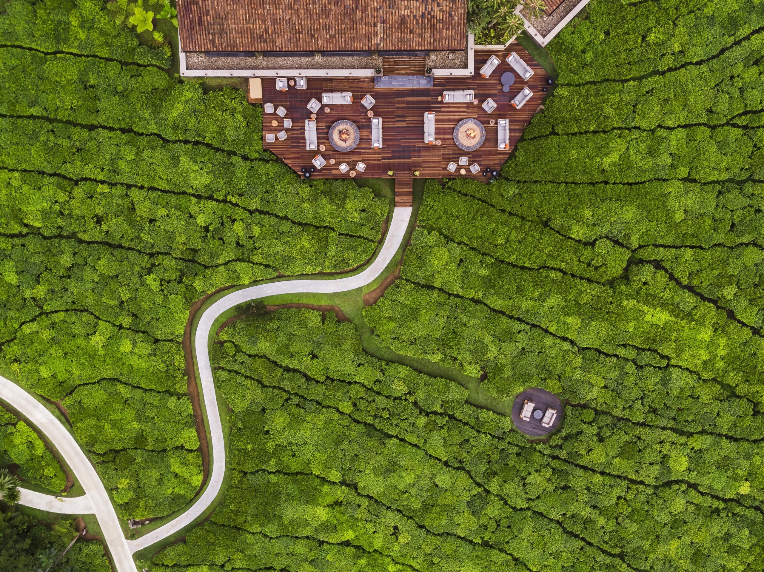 An aerial view shows One&Only Nyungwe House among bright green tea fields and curving pathways in Rwanda.