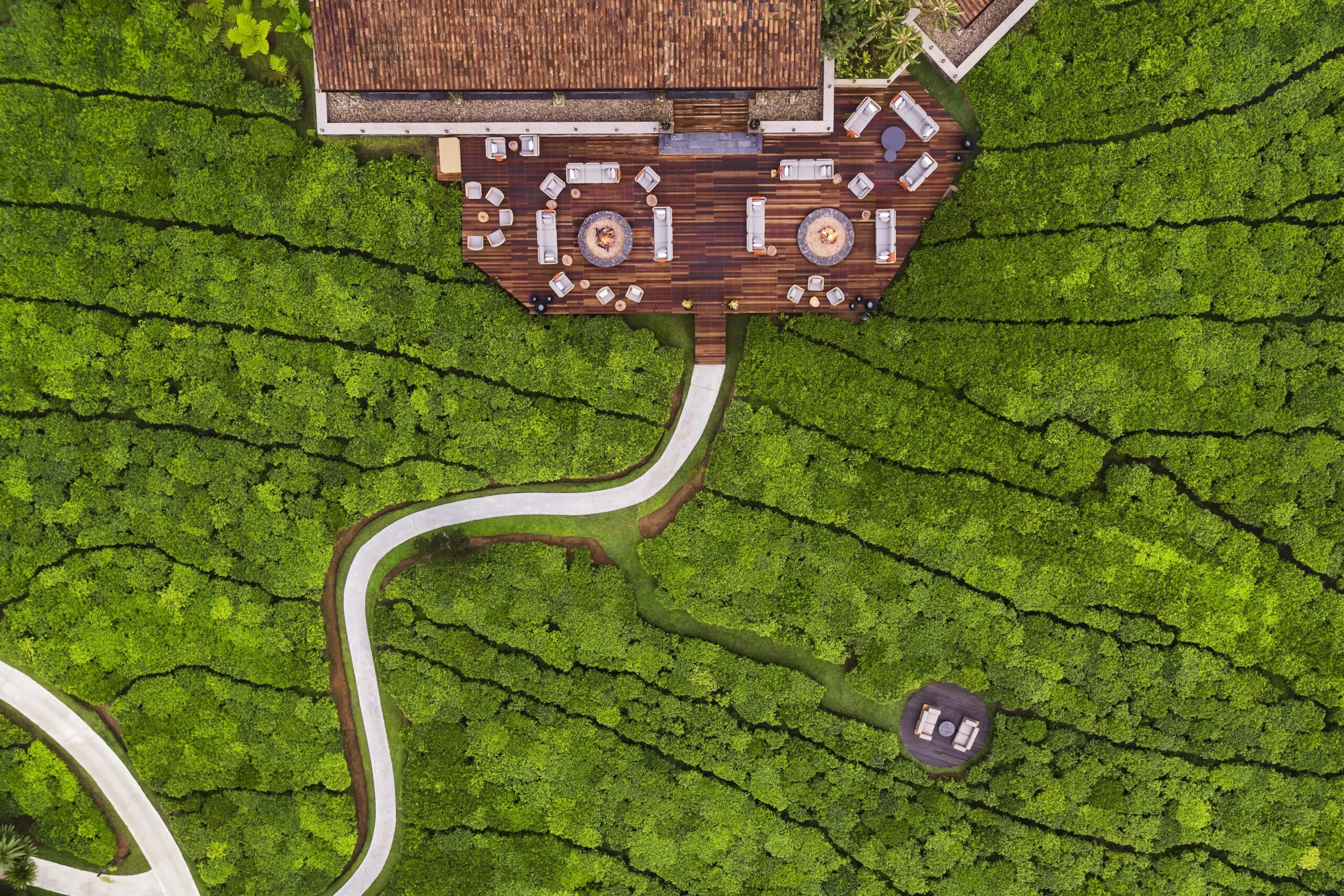 An aerial view shows One&Only Nyungwe House among bright green tea fields and curving pathways in Rwanda.