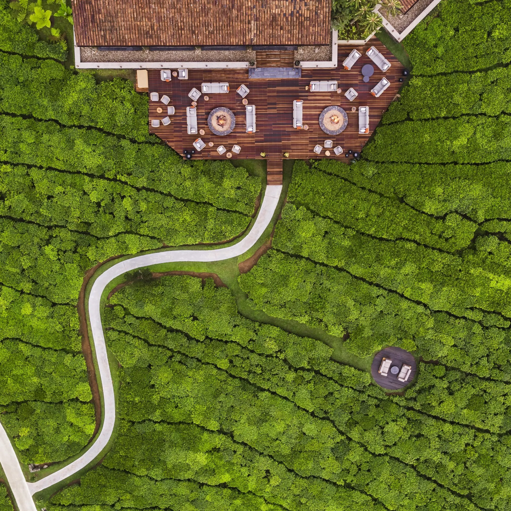 An aerial view shows One&Only Nyungwe House among bright green tea fields and curving pathways in Rwanda.